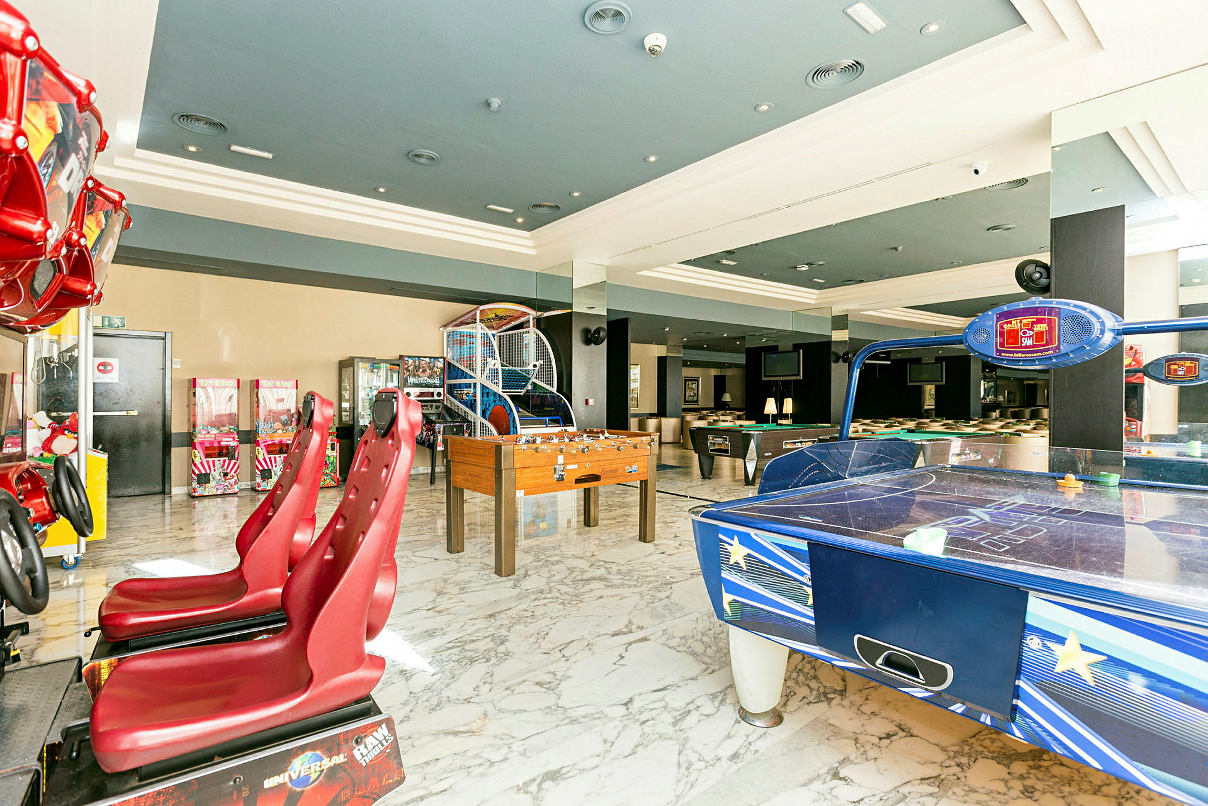 Bild av ett spelrum med olika arkadspel, fotbollspel och air hockey. (AI-genererad text)