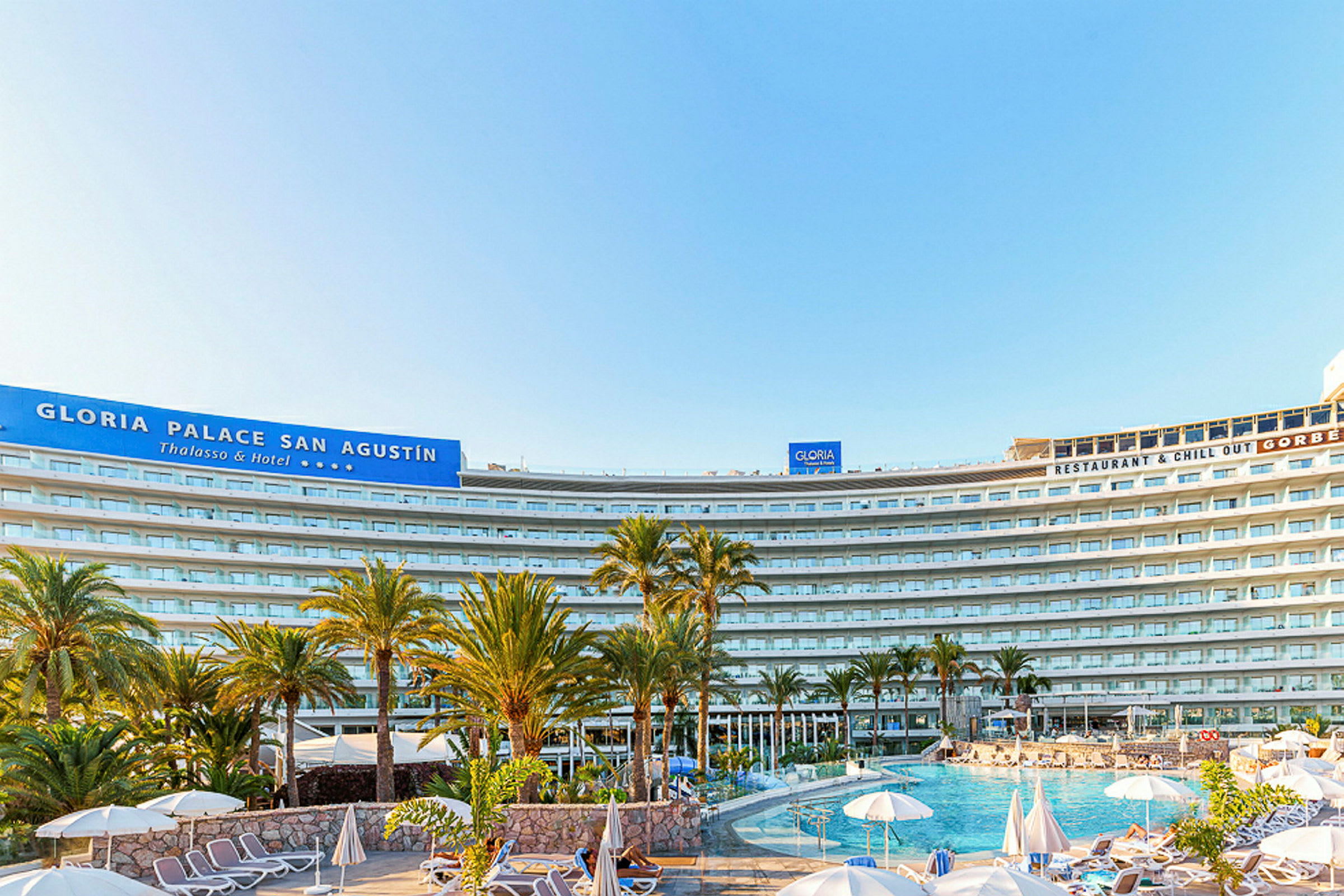 Bild av hotellet Gloria Palace San Agustín med pool och solstolar i förgrunden. (AI-genererad text)