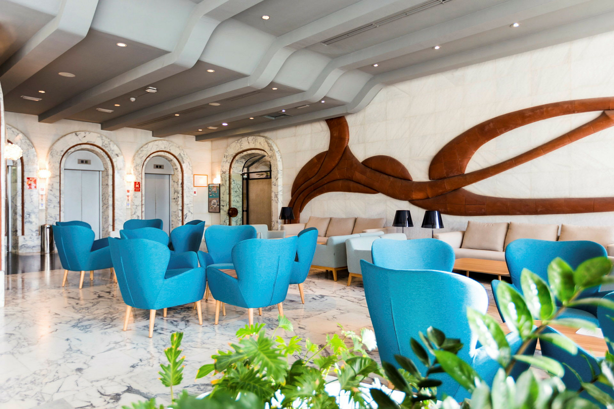 Modern hotellobby med blå fåtöljer och dekorativ vägg. (AI-genererad text)