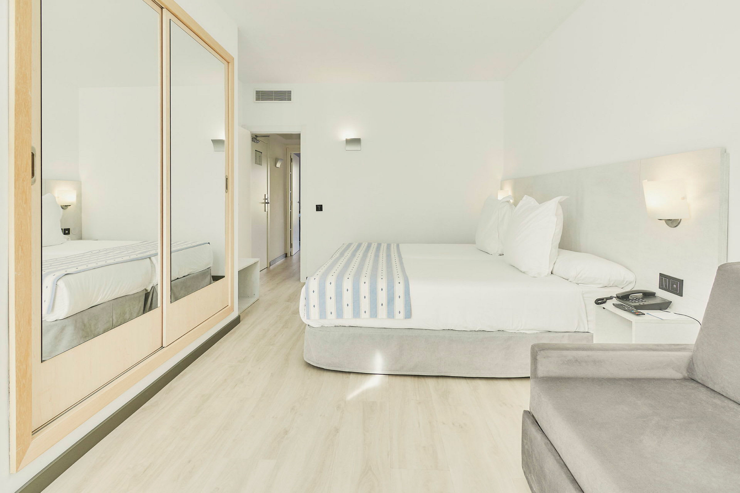 Ett hotellrum med en dubbelsäng och ljusa möbler. (AI-genererad text)
