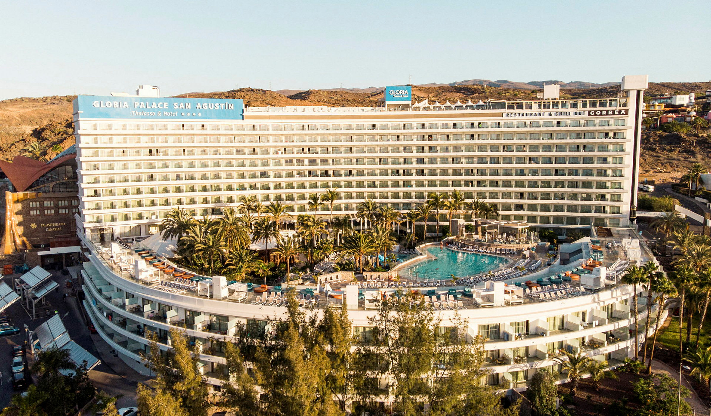 Hotellbyggnad med pool och omgivande grönska. (AI-genererad text)