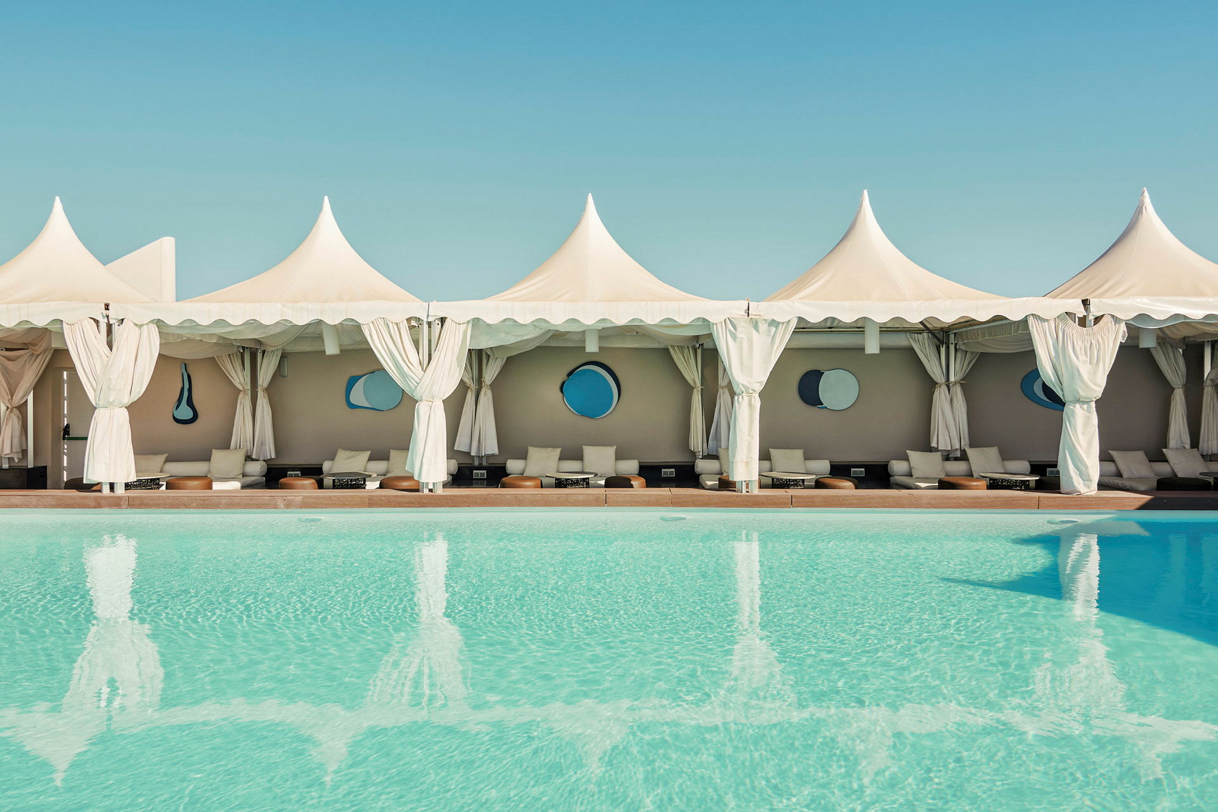 Pool med cabanas och vita tält i bakgrunden. (AI-genererad text)