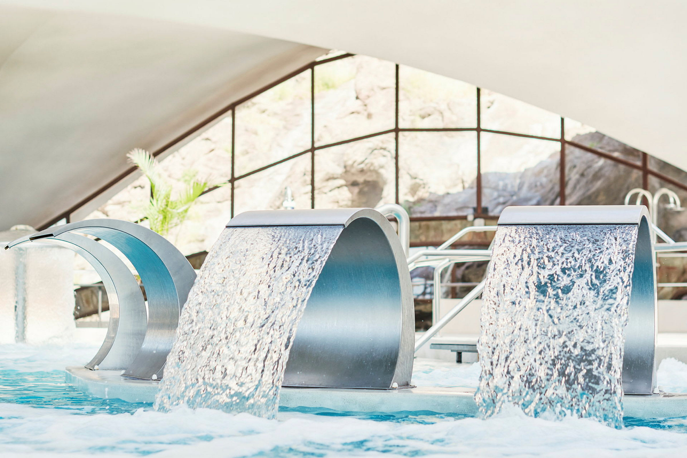 Två vattenfontäner i en pool inomhus. (AI-genererad text)