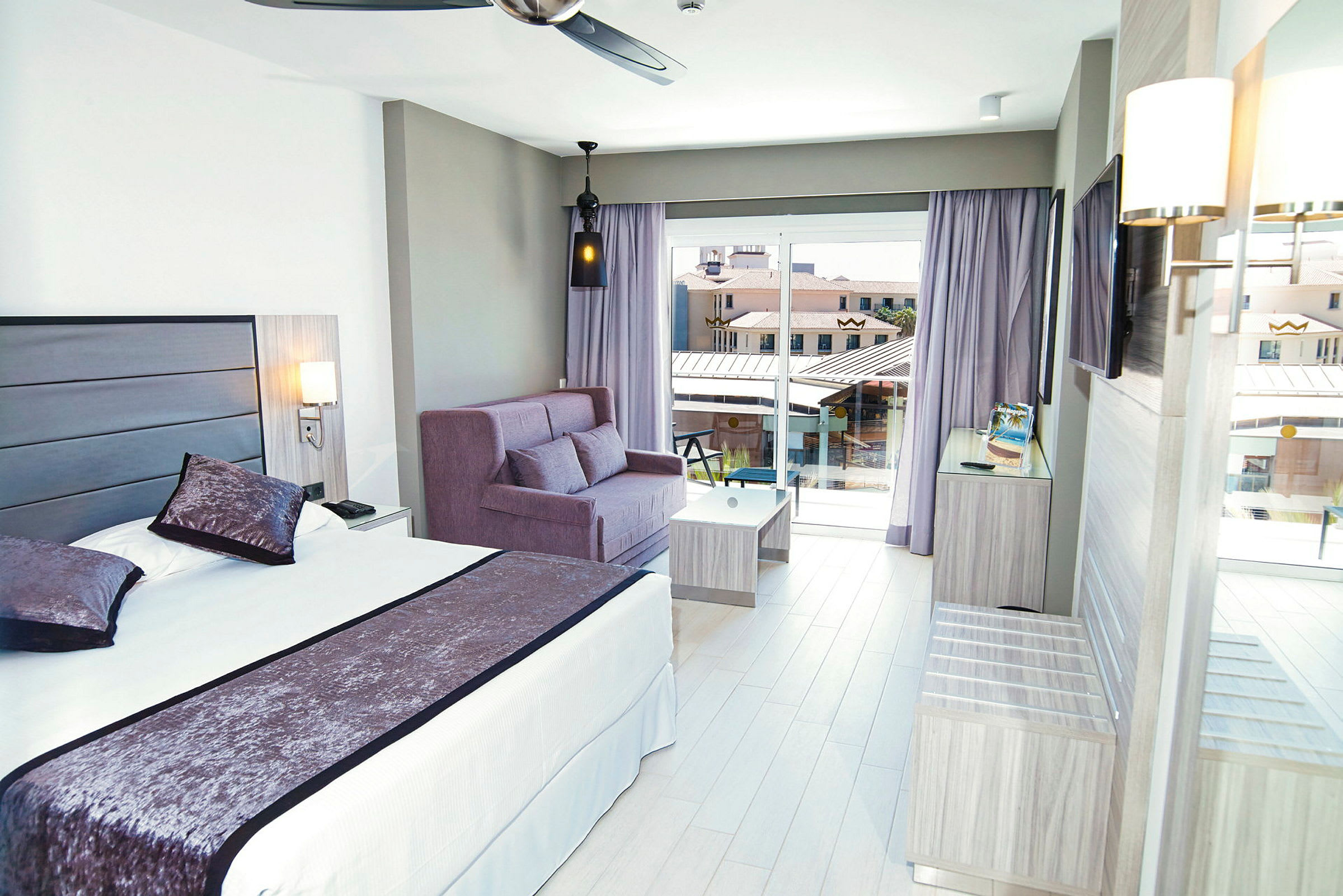 Hotellrum med säng, soffa, och balkongutsikt. (AI-genererad text)