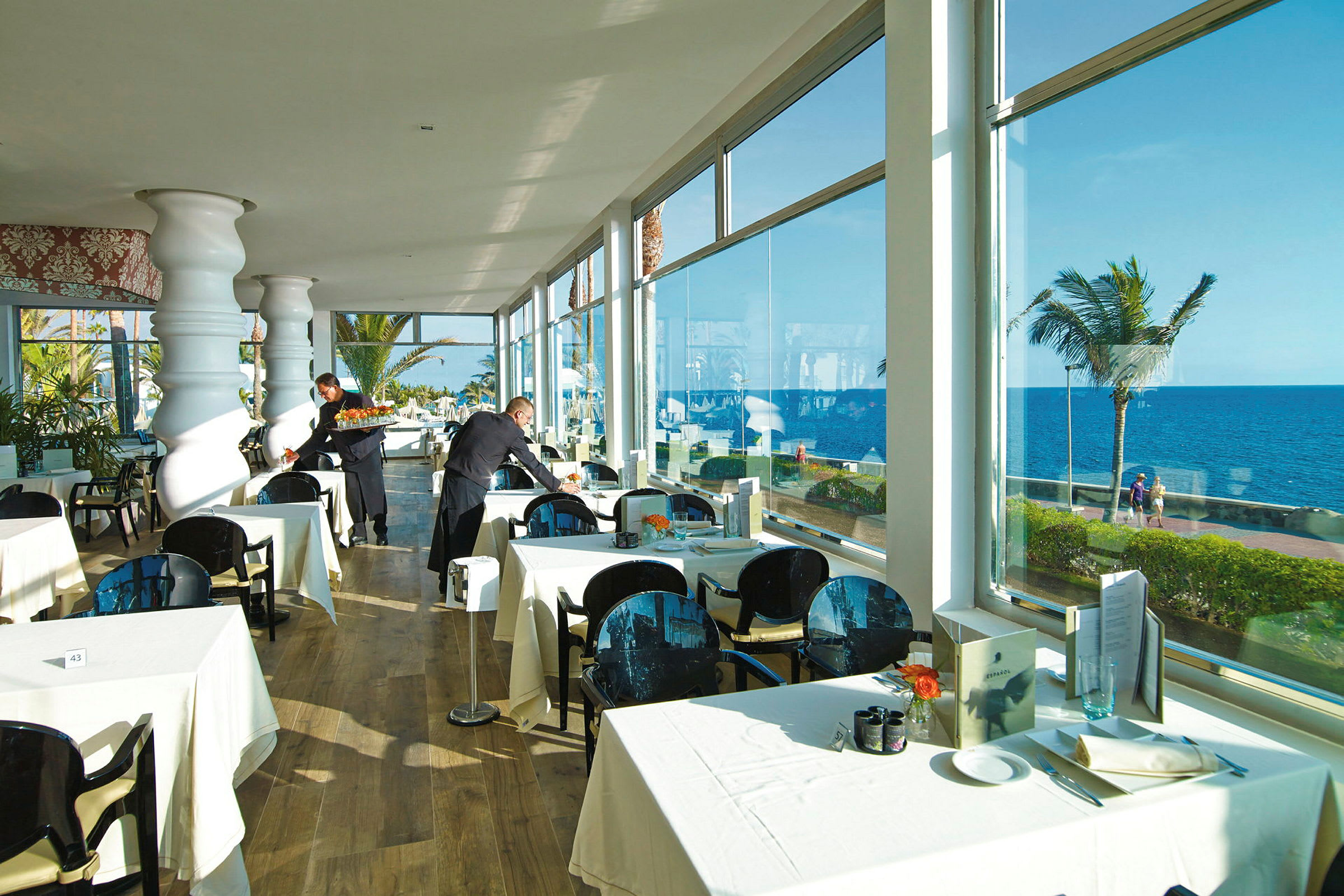 Restaurang med dukade bord nära fönster med havsutsikt. (AI-genererad text)