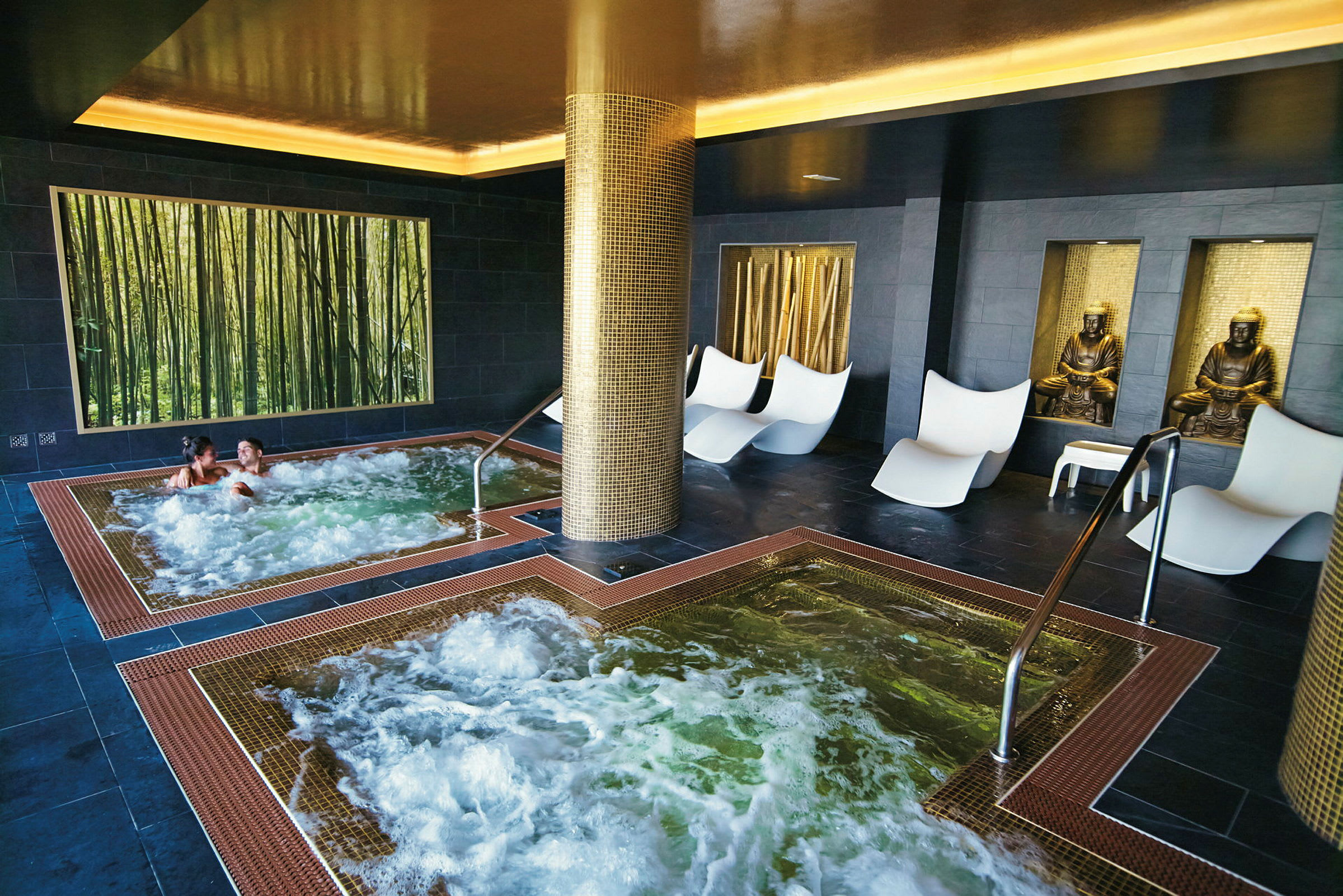 Inomhusspa med bubbelpooler, sittplatser och dekorativa statyer. (AI-genererad text)