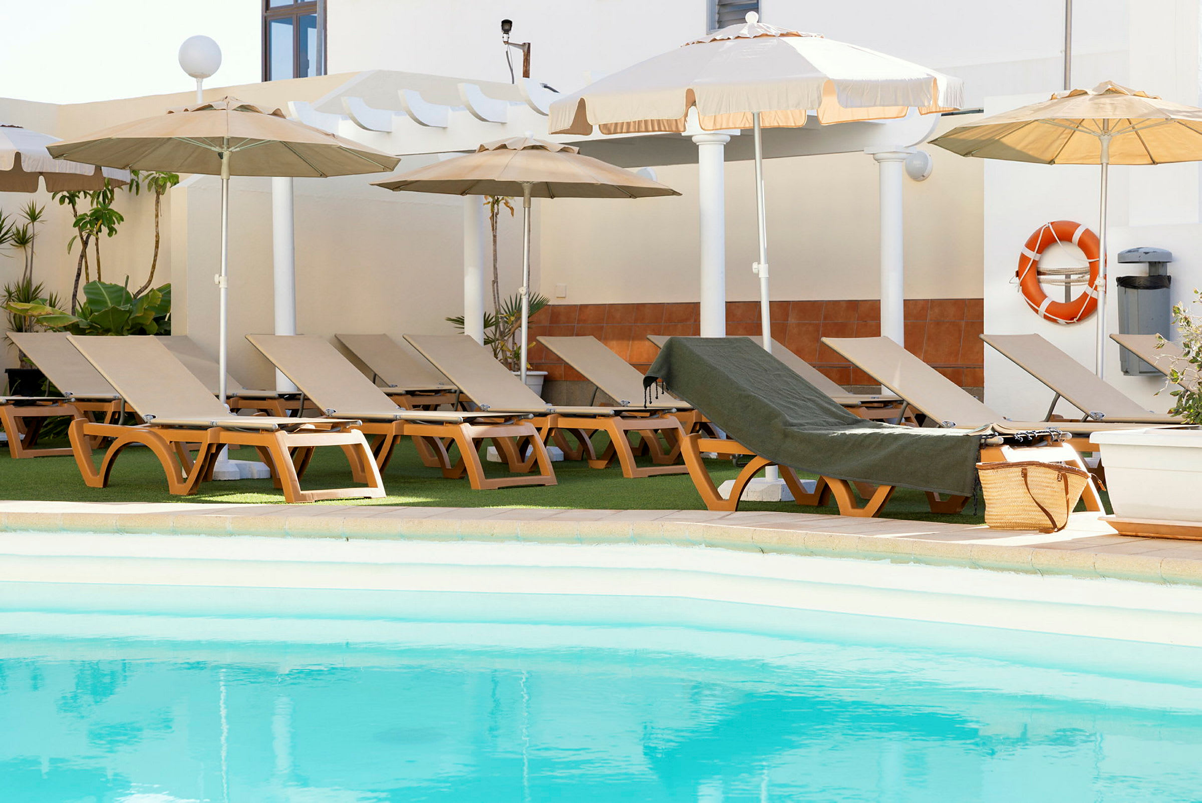 Solstolar med parasoll vid en pool. (AI-genererad text)