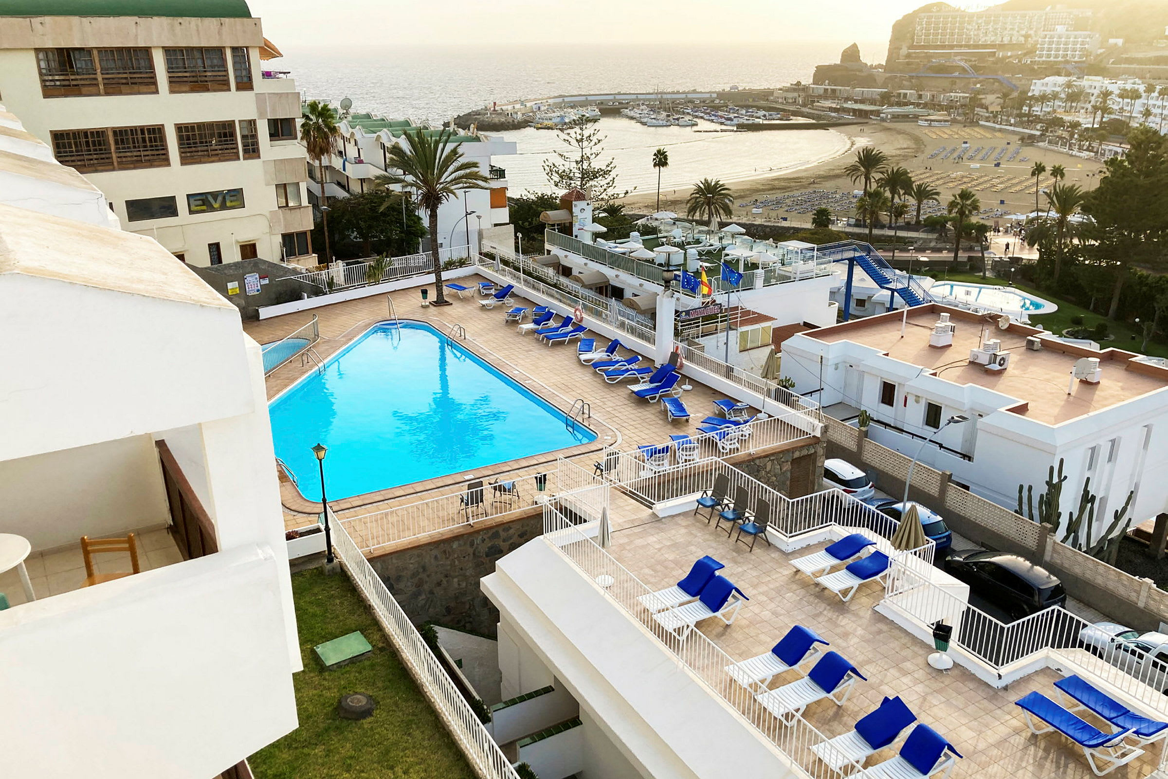 Utsikt över en hotellpool och solstolar med havet i bakgrunden. (AI-genererad text)