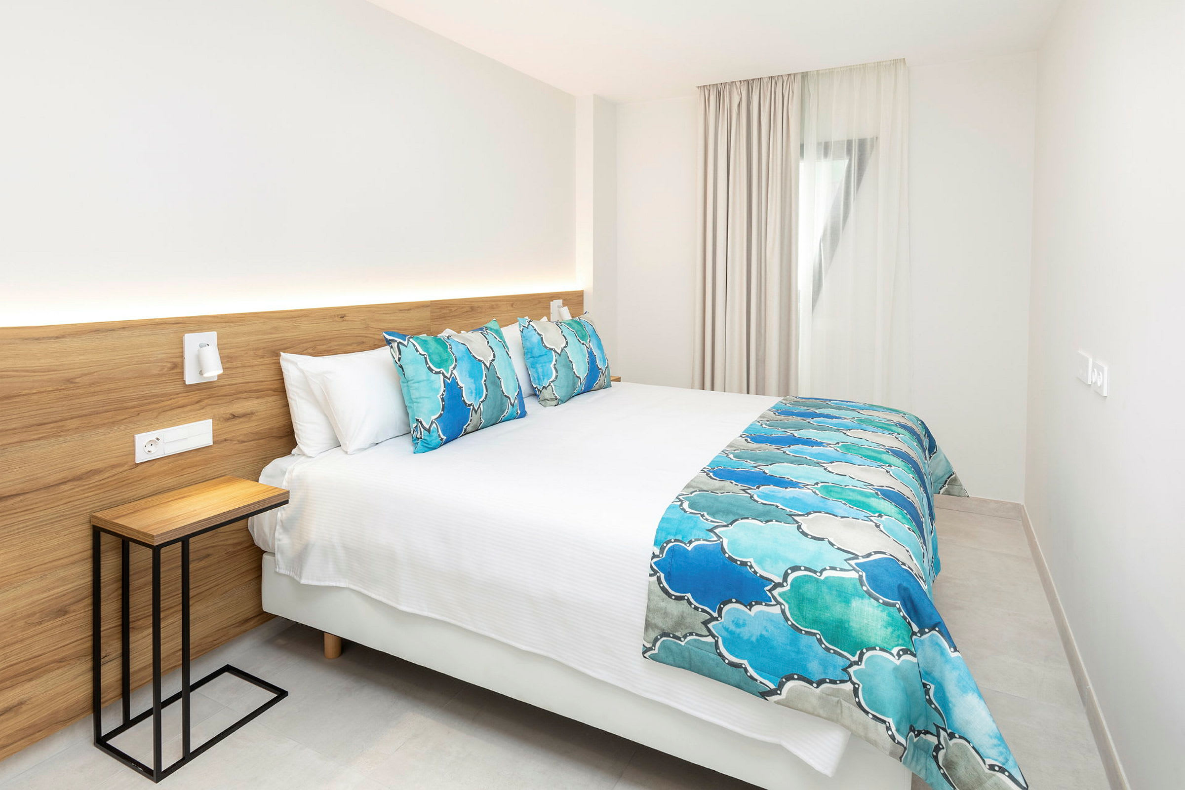 Modernt hotellrum med en dubbelsäng med blå och vita sängkläder. (AI-genererad text)
