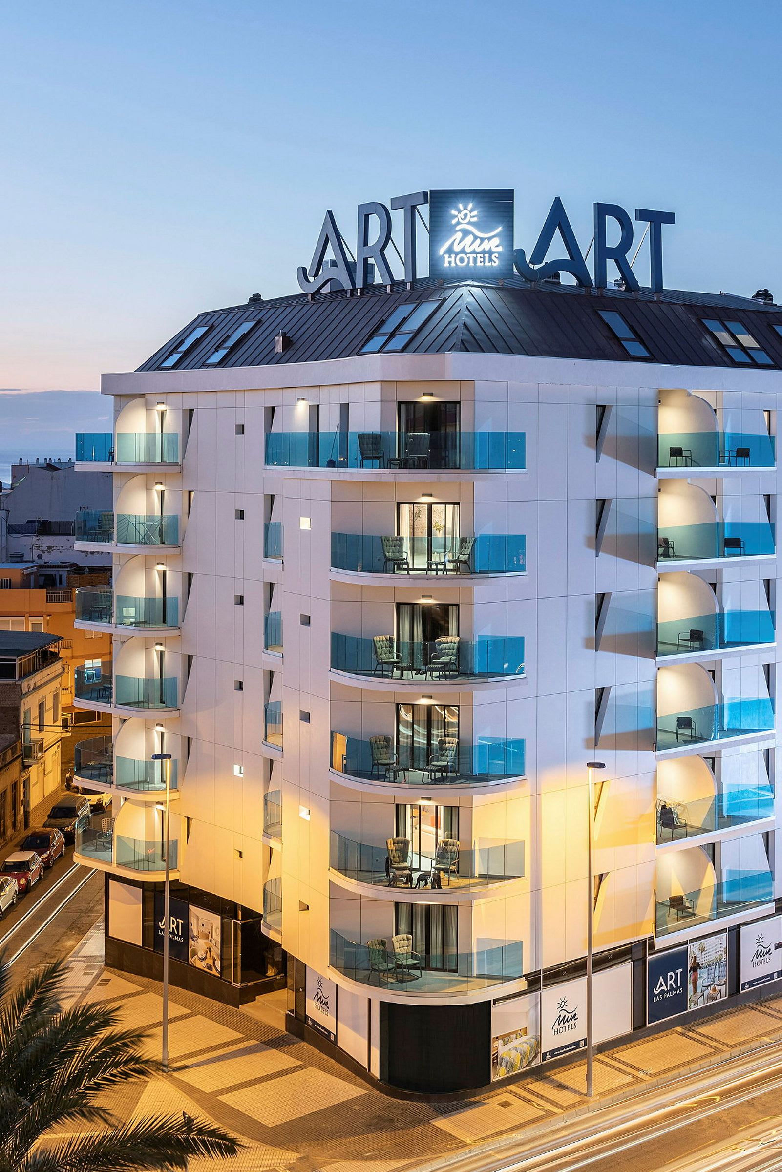 En modern hotellbyggnad med glasbalkonger och skyltar under en kvällshimmel. (AI-genererad text)