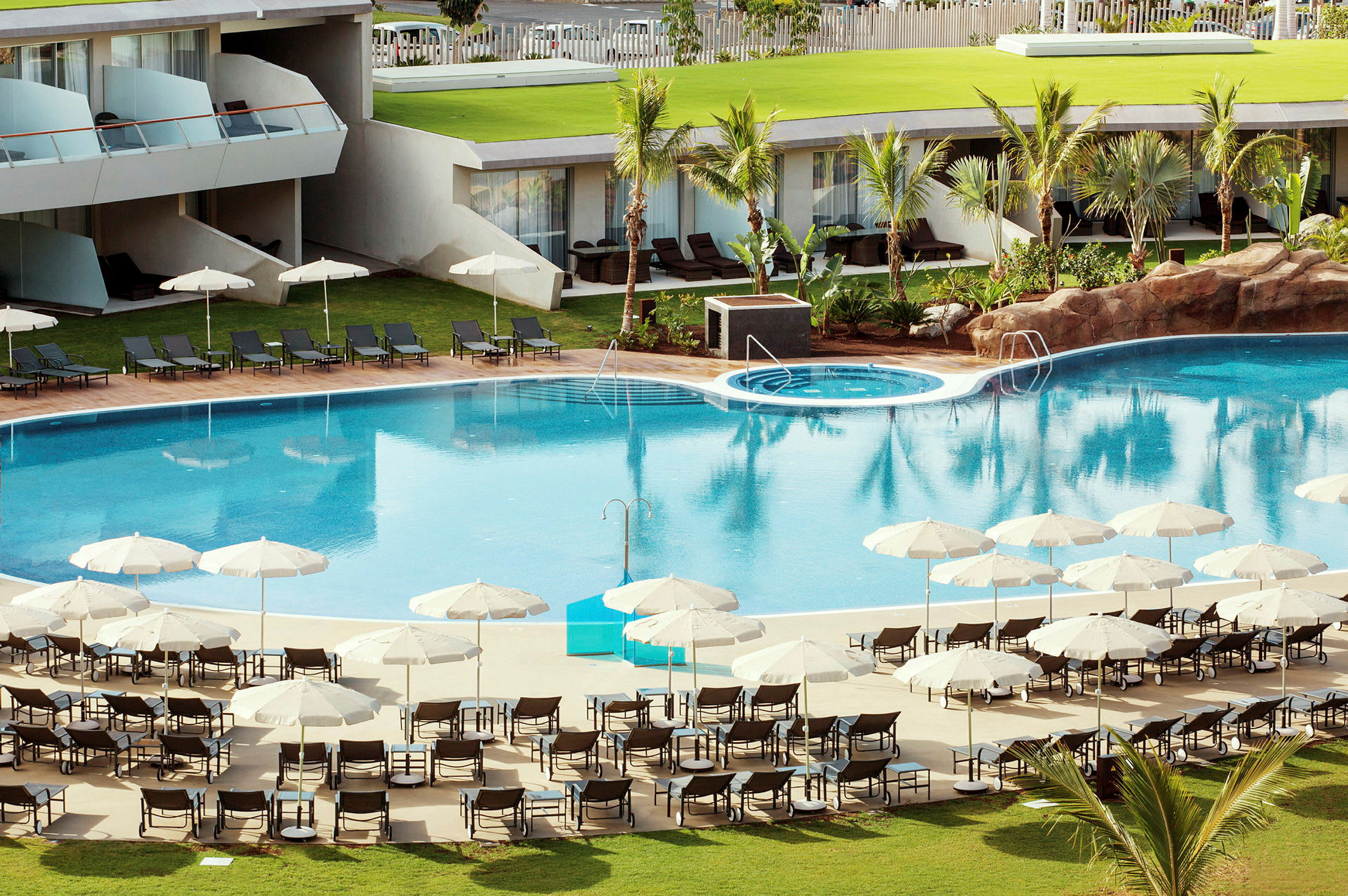 En hotellpool med solstolar och parasoller runt omkring. (AI-genererad text)