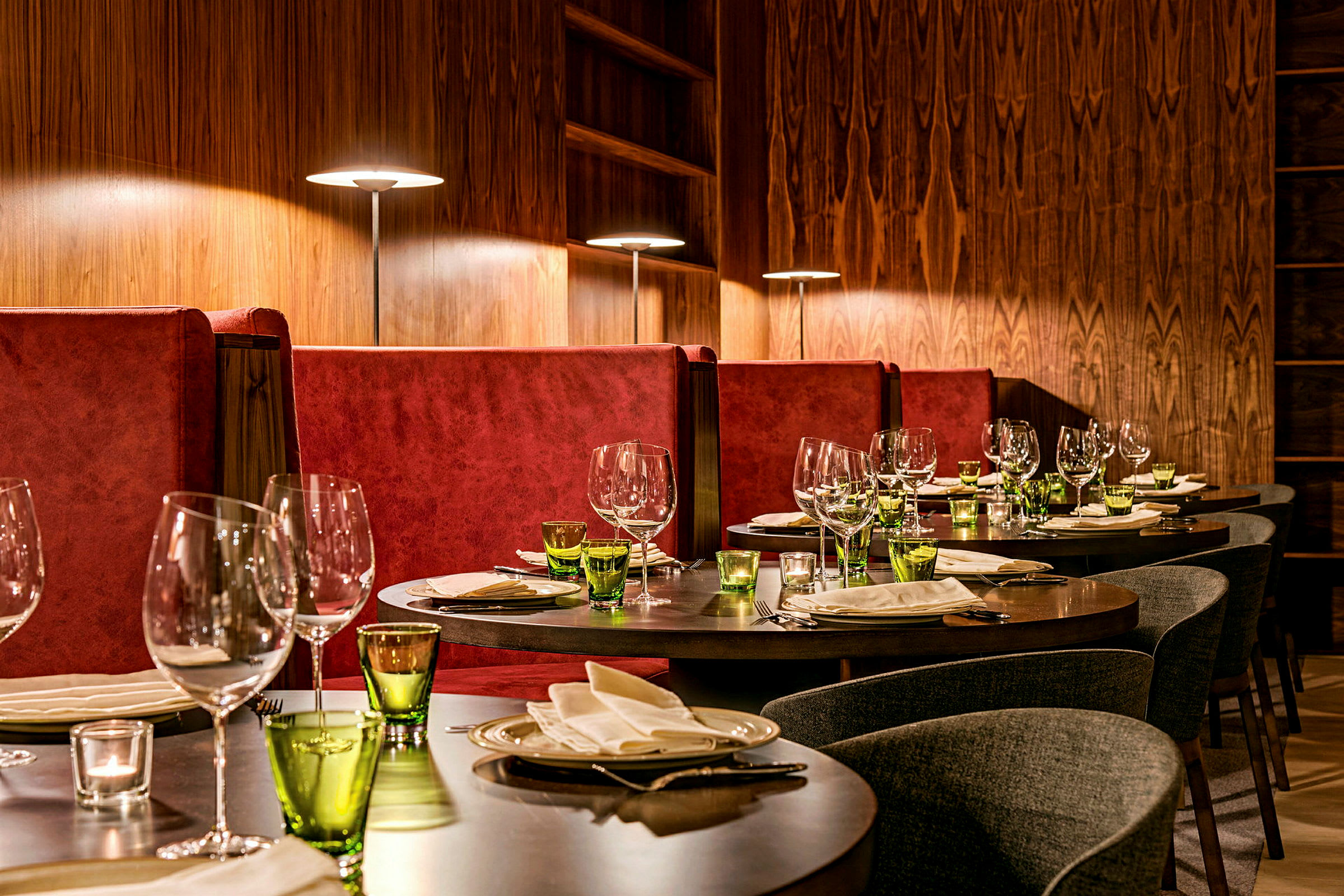 Elegant restaurang med dukade bord och röda soffor. (AI-genererad text)