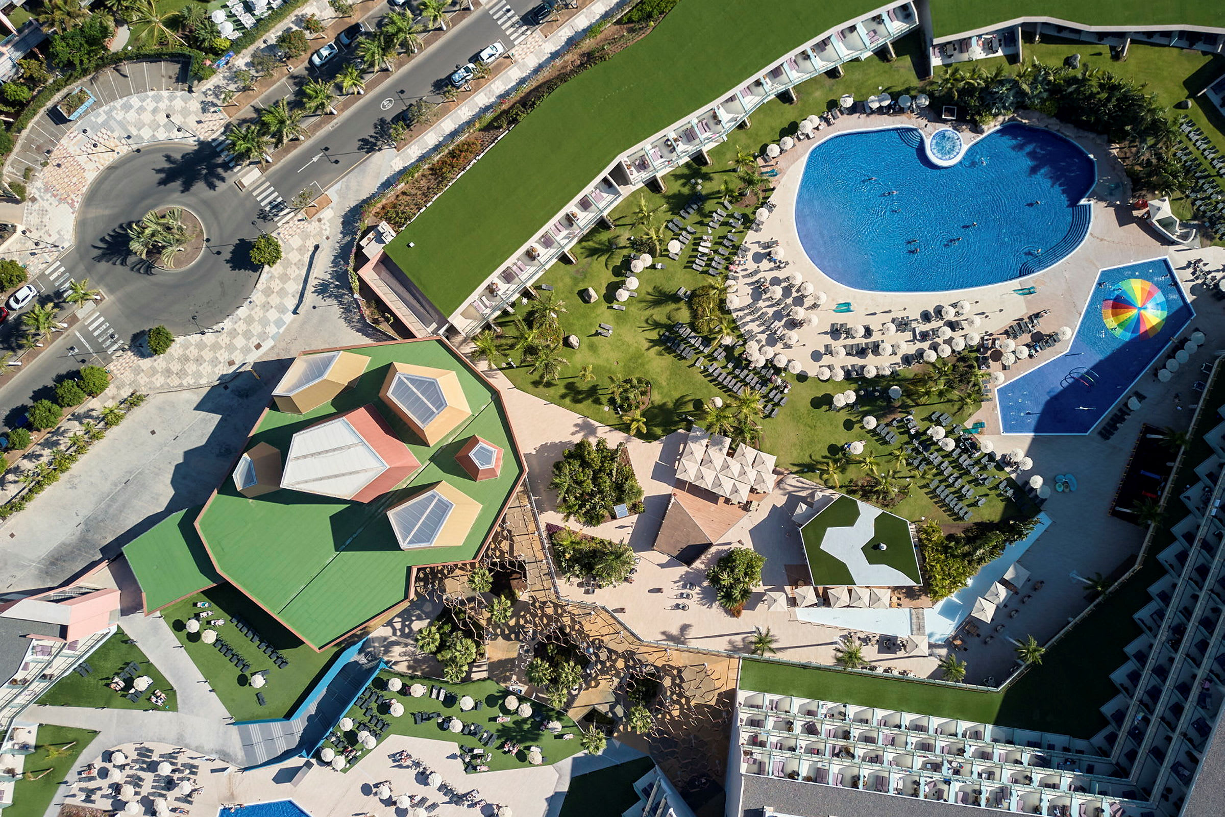 Flygvy över en resort med poolområde, grönområden och byggnader. (AI-genererad text)