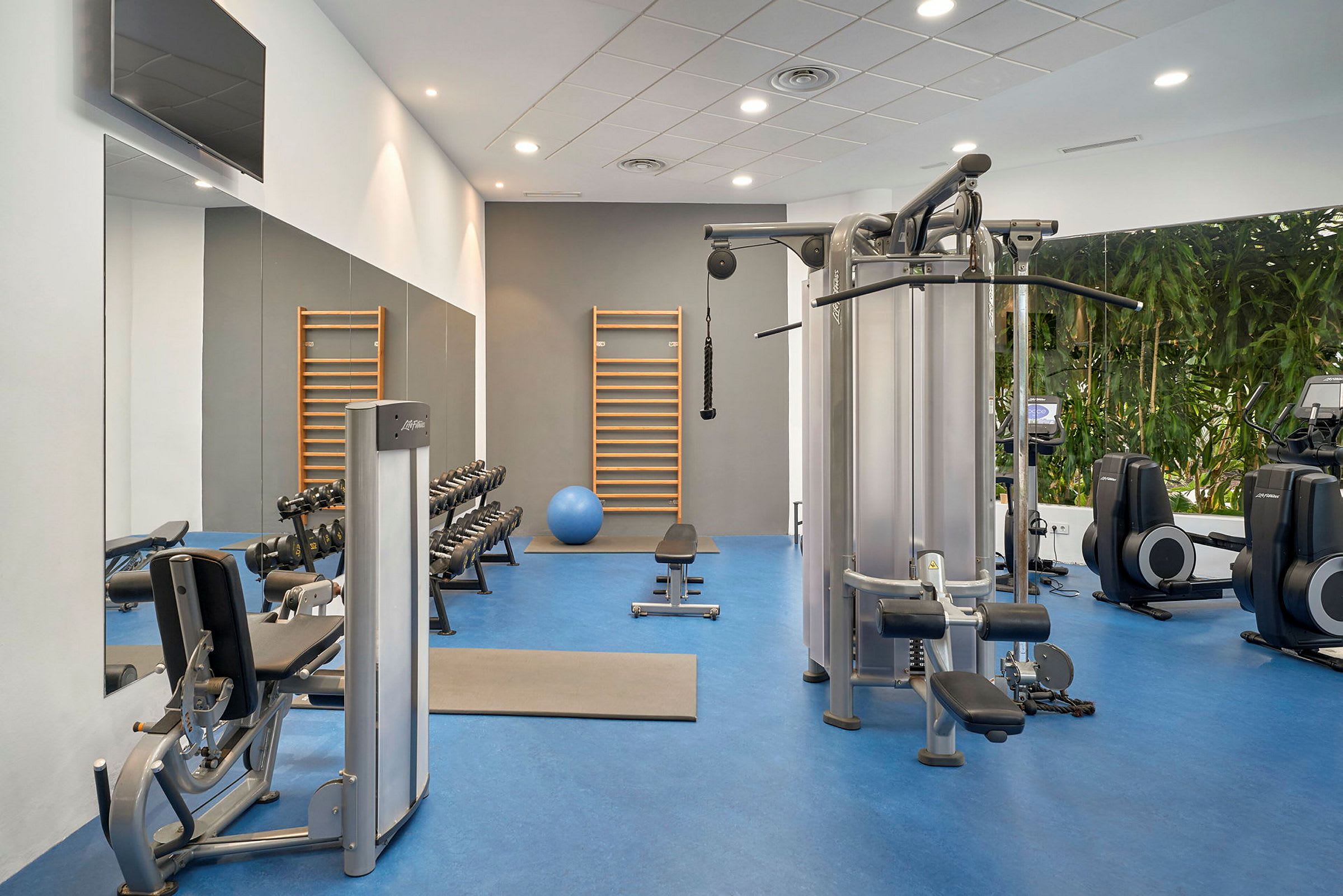 Ett gym med olika träningsmaskiner, hantlar och en balansboll. (AI-genererad text)
