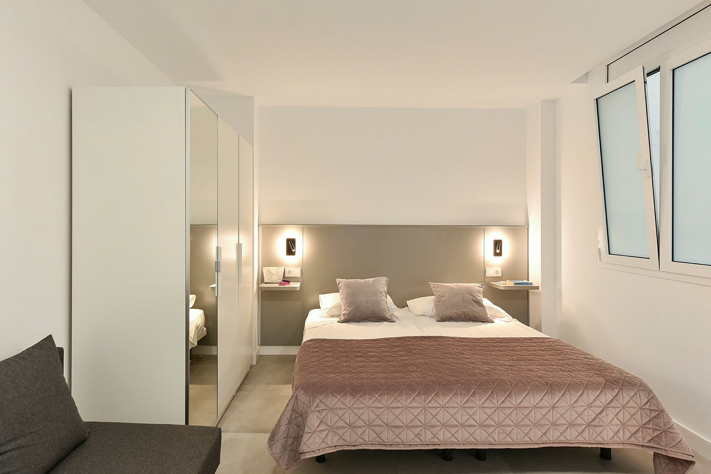 Ett hotellrum med en dubbelsäng, en rosa sängöverkast och garderob. (AI-genererad text)