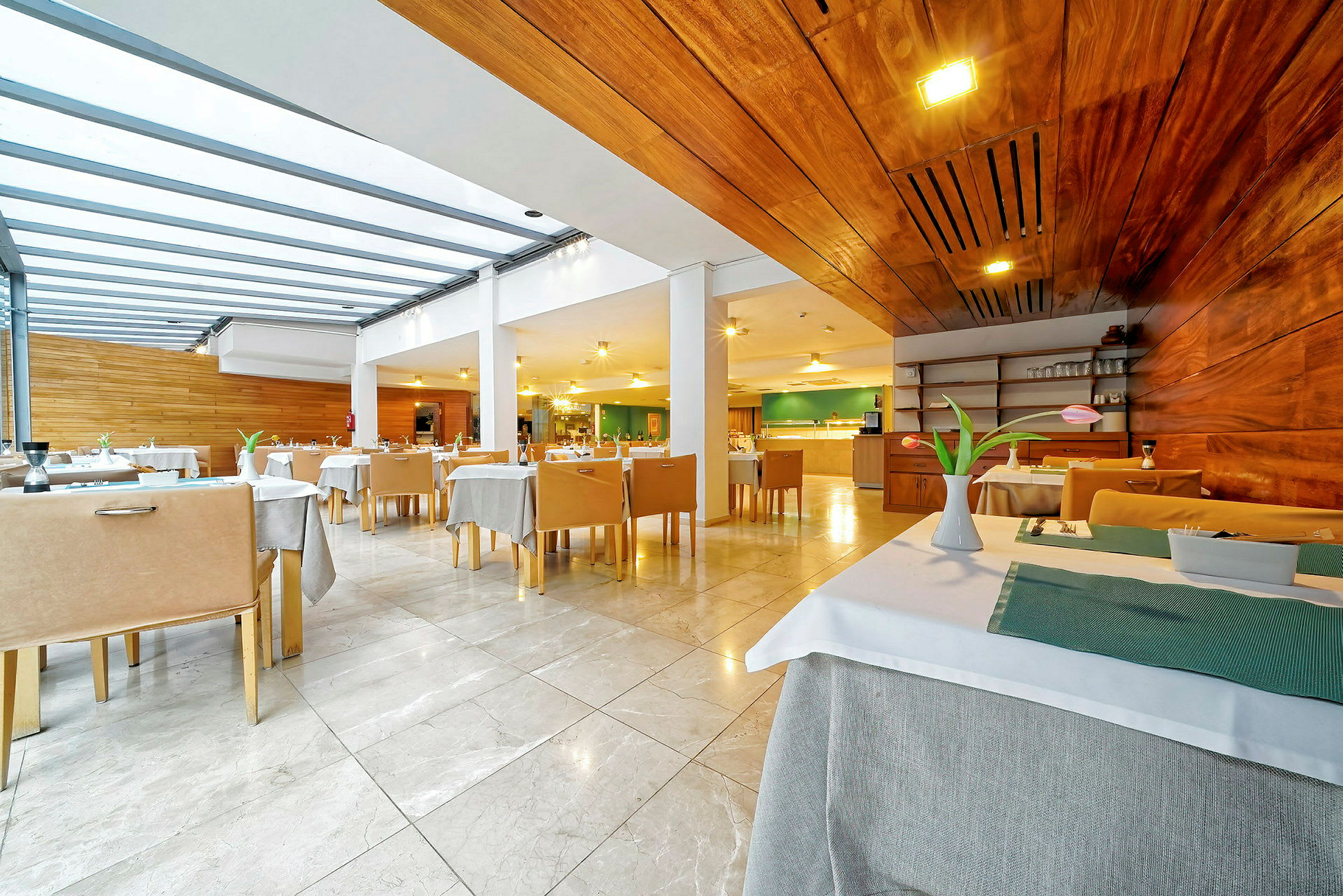 En modern restaurang med träpaneler, dukade bord och vita stolar. (AI-genererad text)