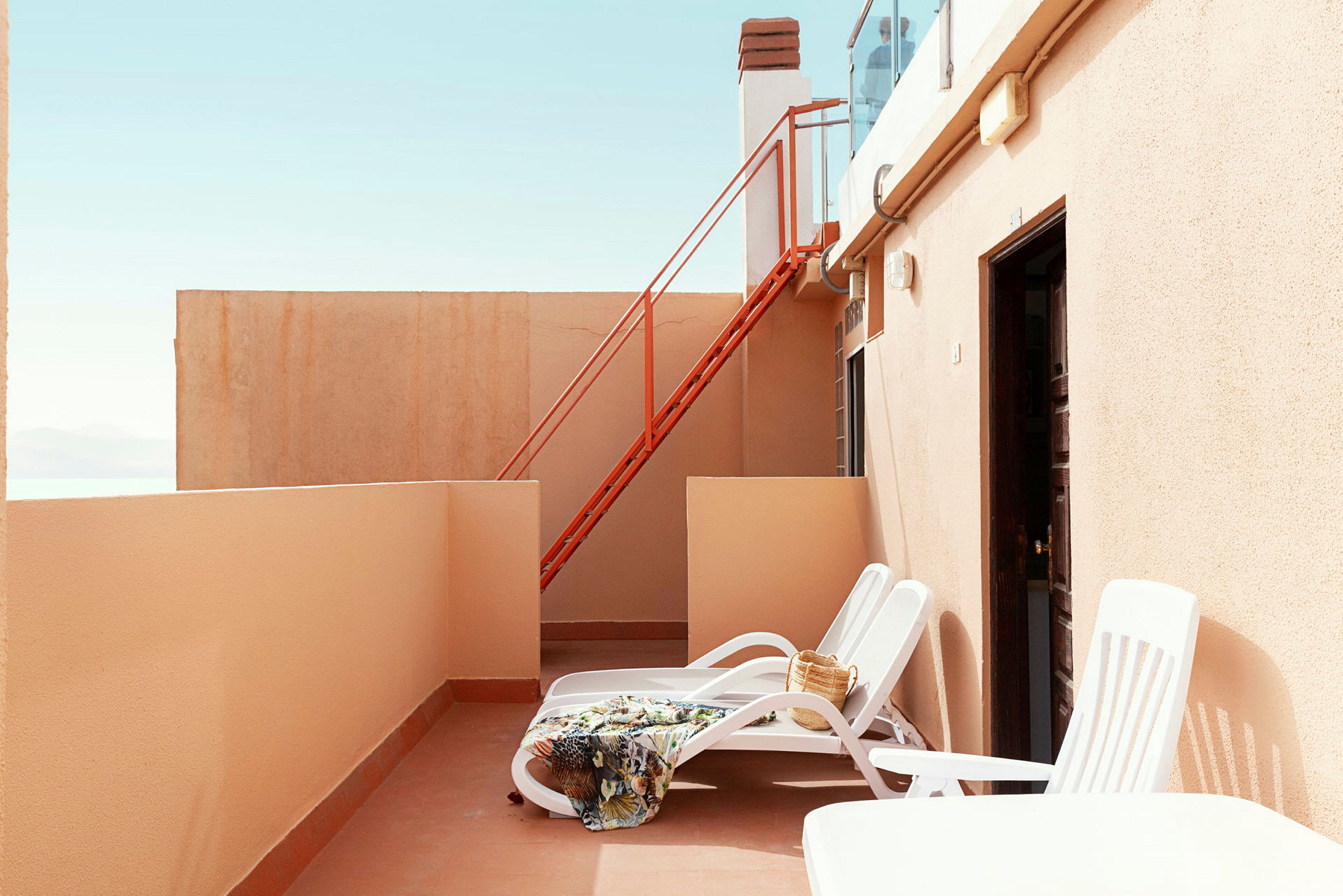 Privat terrass med solstolar, filt och väska. (AI-genererad text)