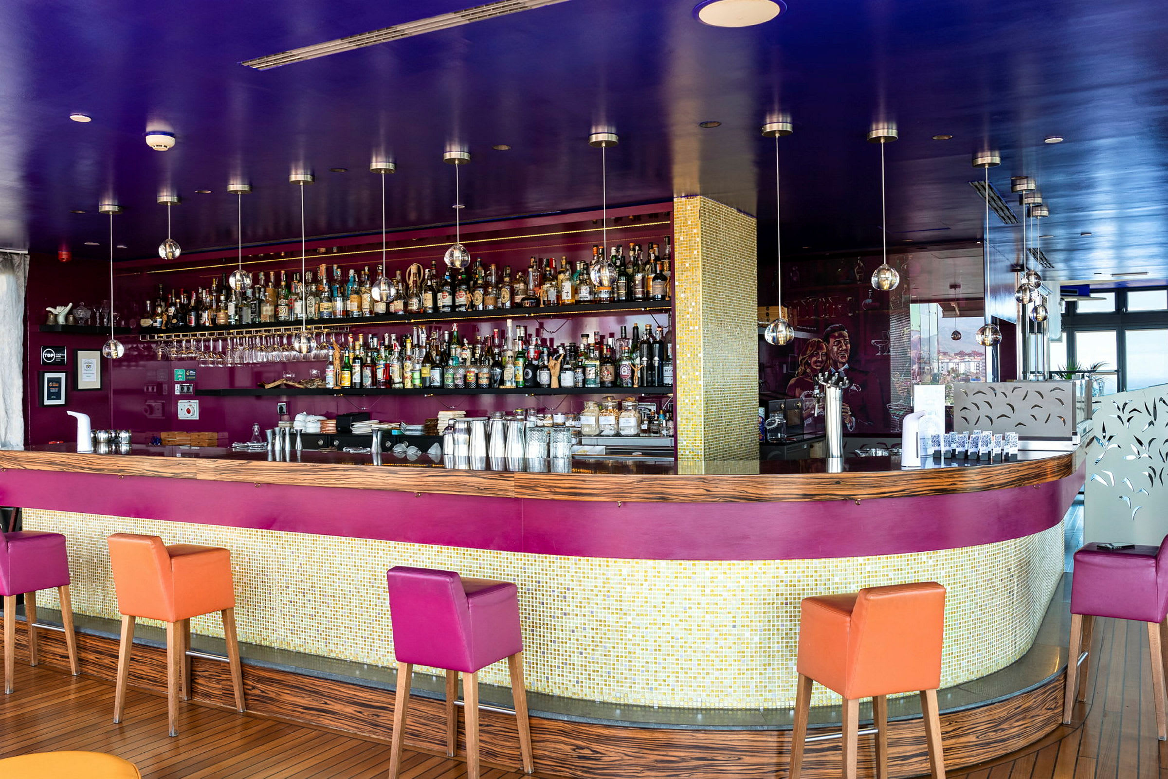 En bild av en modern bar med en lila och träfärgad diskinredning samt färgglada stolar. (AI-genererad text)