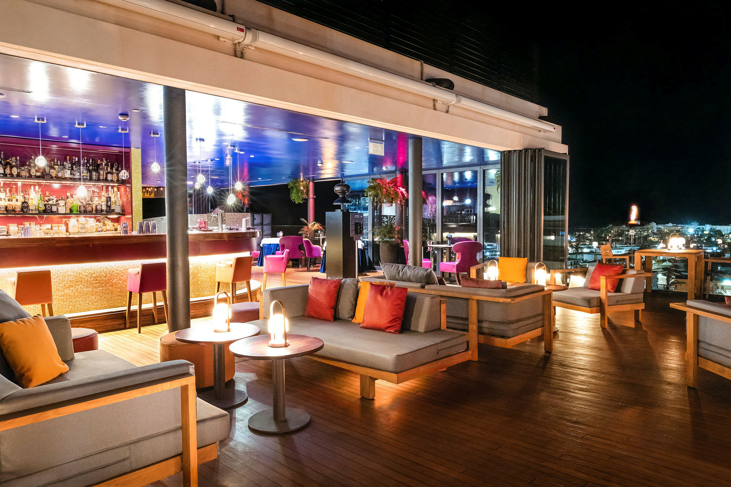 En takterrassbar med sittplatser och belysning på natten. (AI-genererad text)