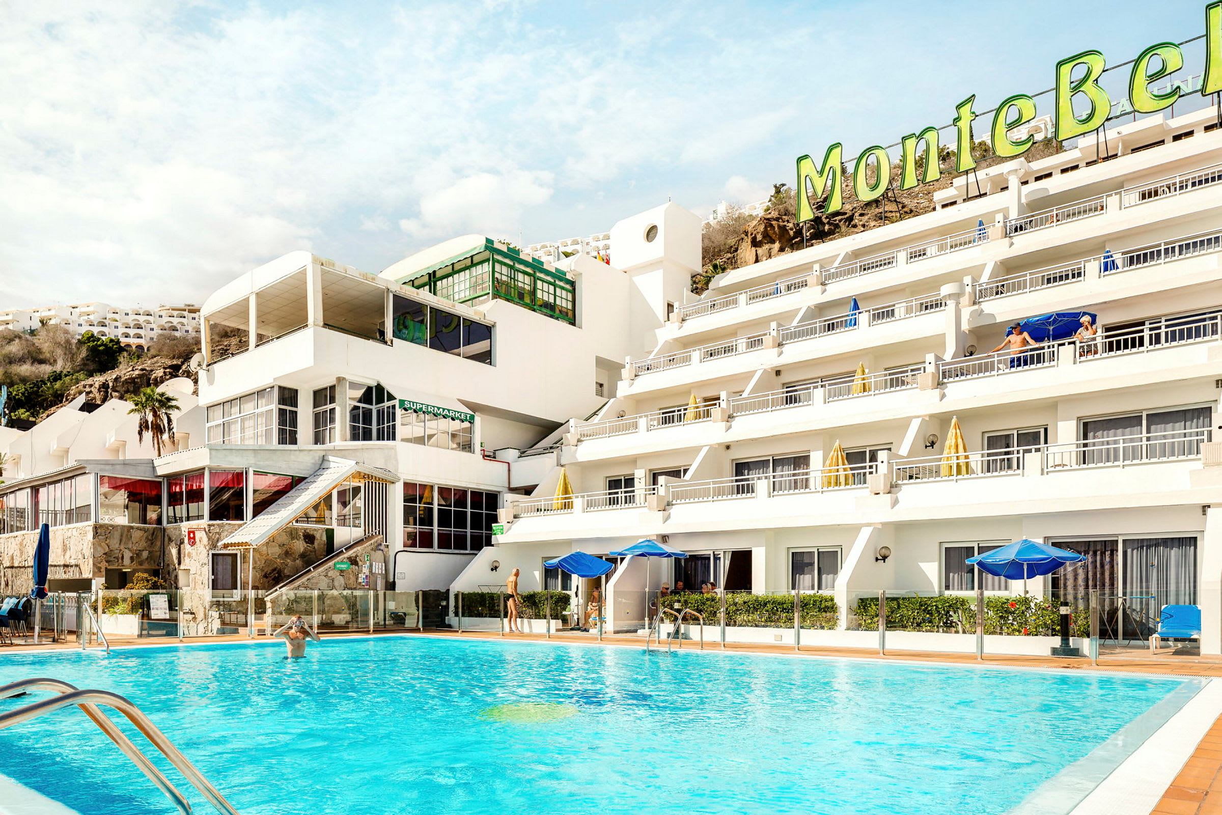 Hotell med poolområde och ljusa byggnader. (AI-genererad text)