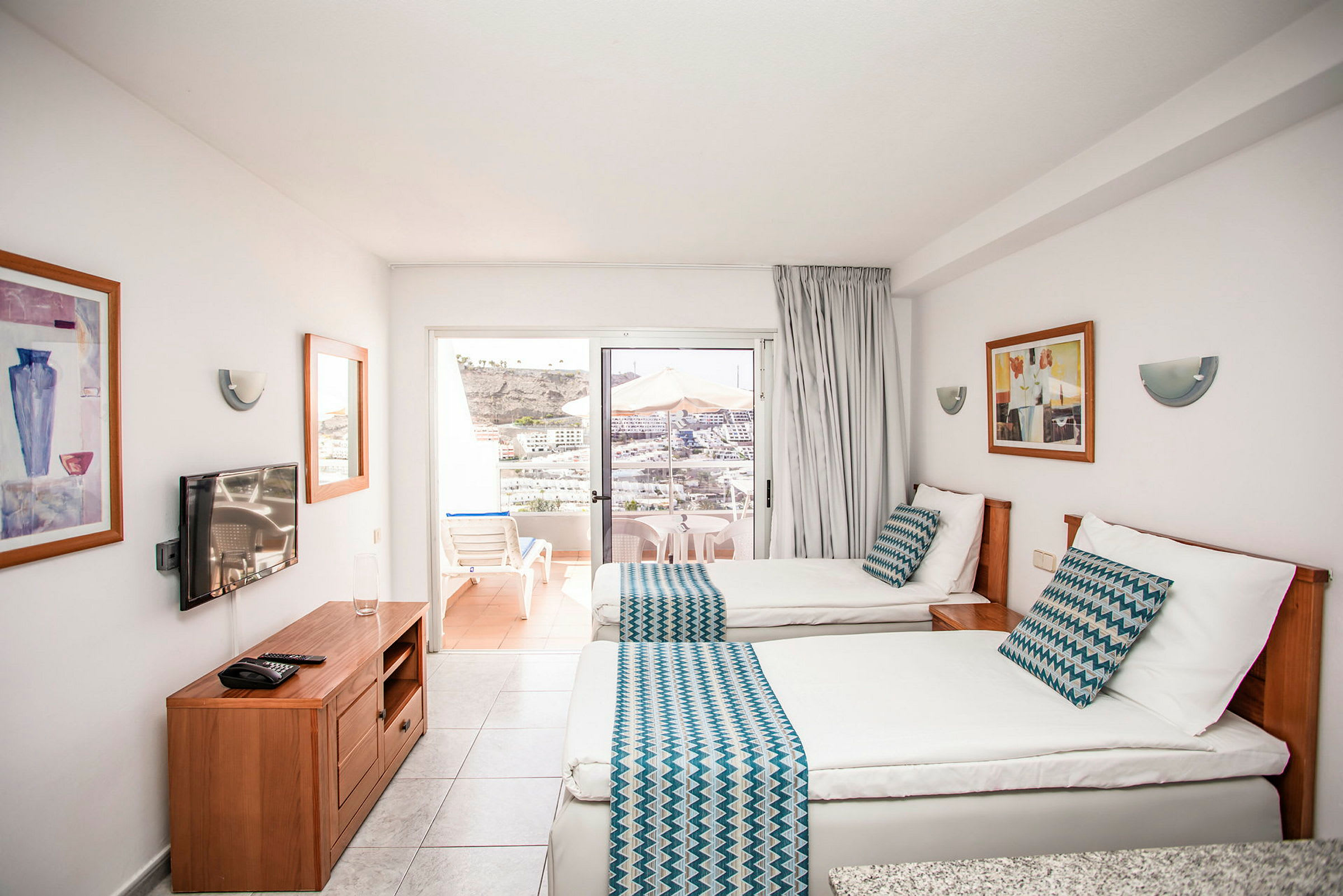 Hotellrum med två enkelsängar, balkong med utsikt över omgivningen. (AI-genererad text)