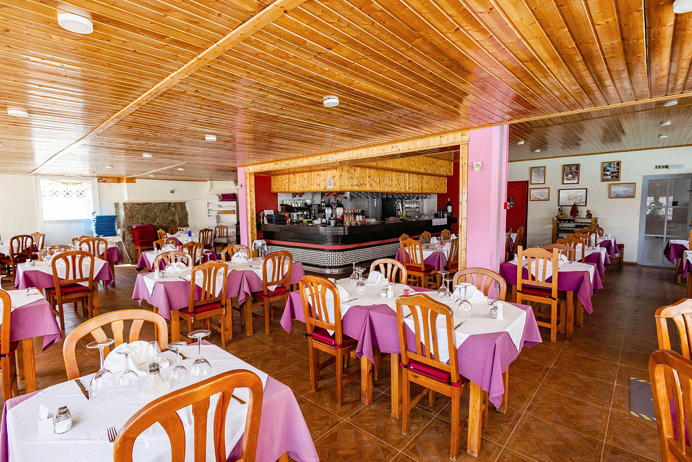 En restaurang med träinredning, lila dukar på borden och stolar i trä. (AI-genererad text)