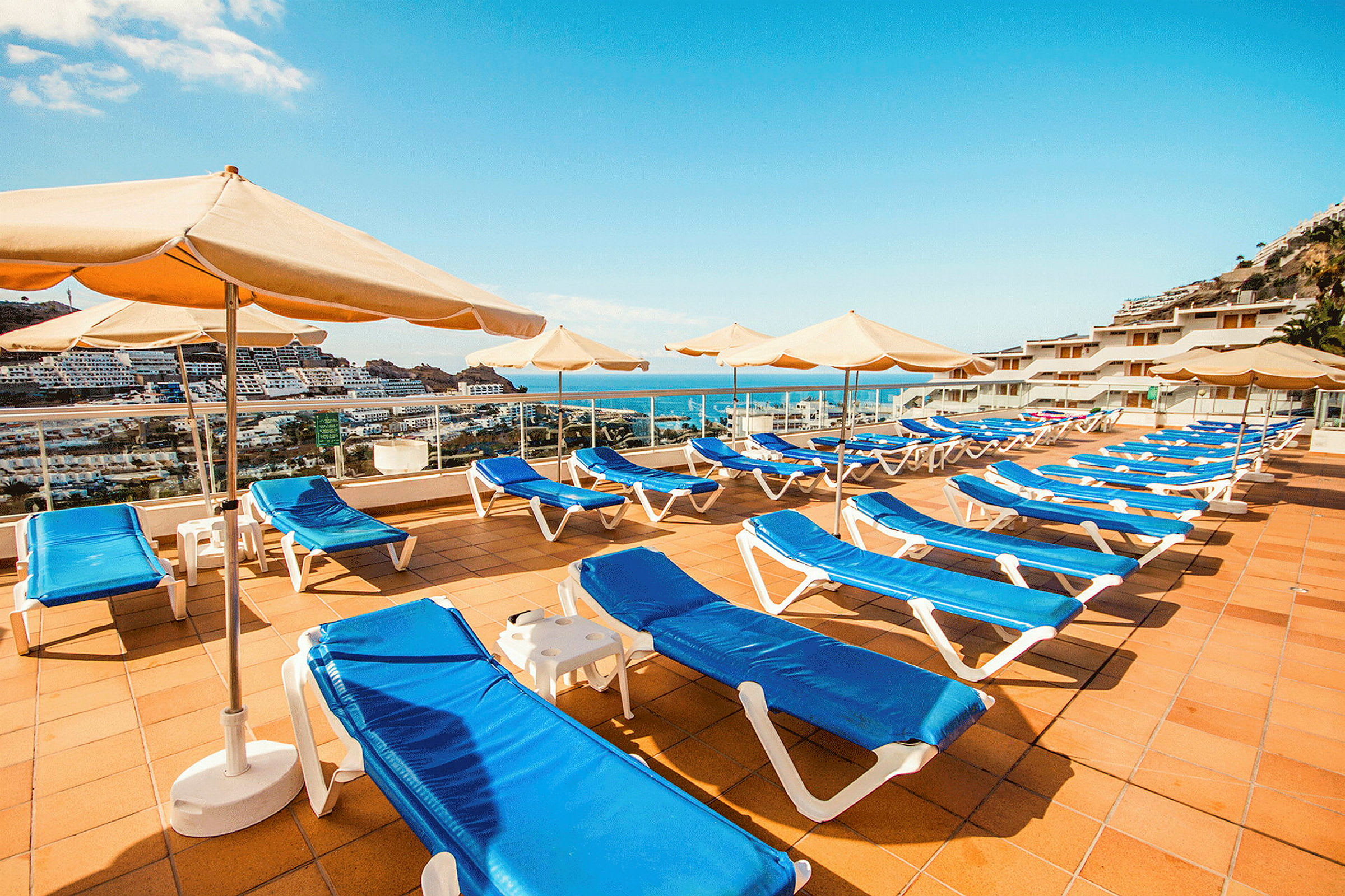 Solstolar och parasoller på en solterrass med havsutsikt. (AI-genererad text)