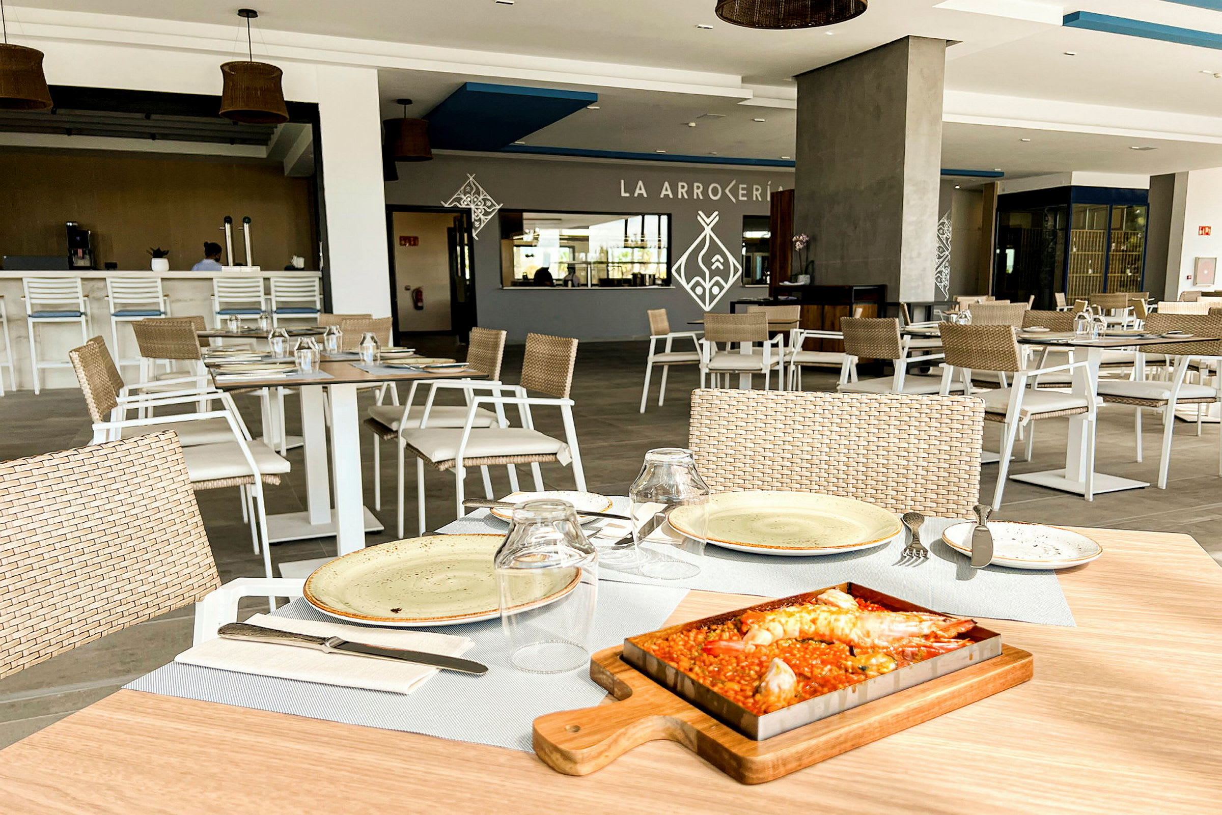 Bild av en restaurang med dukade bord och serverad maträtt, en paella. (AI-genererad text)