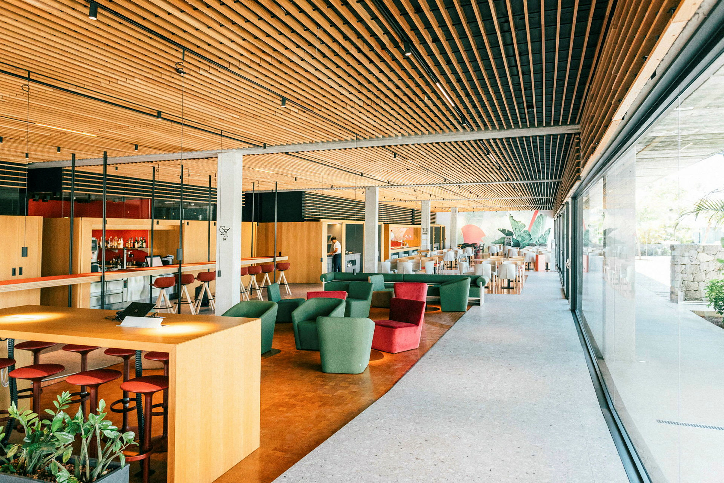 Interiör av en modern lounge med sittplatser, barområde och stora fönster. (AI-genererad text)