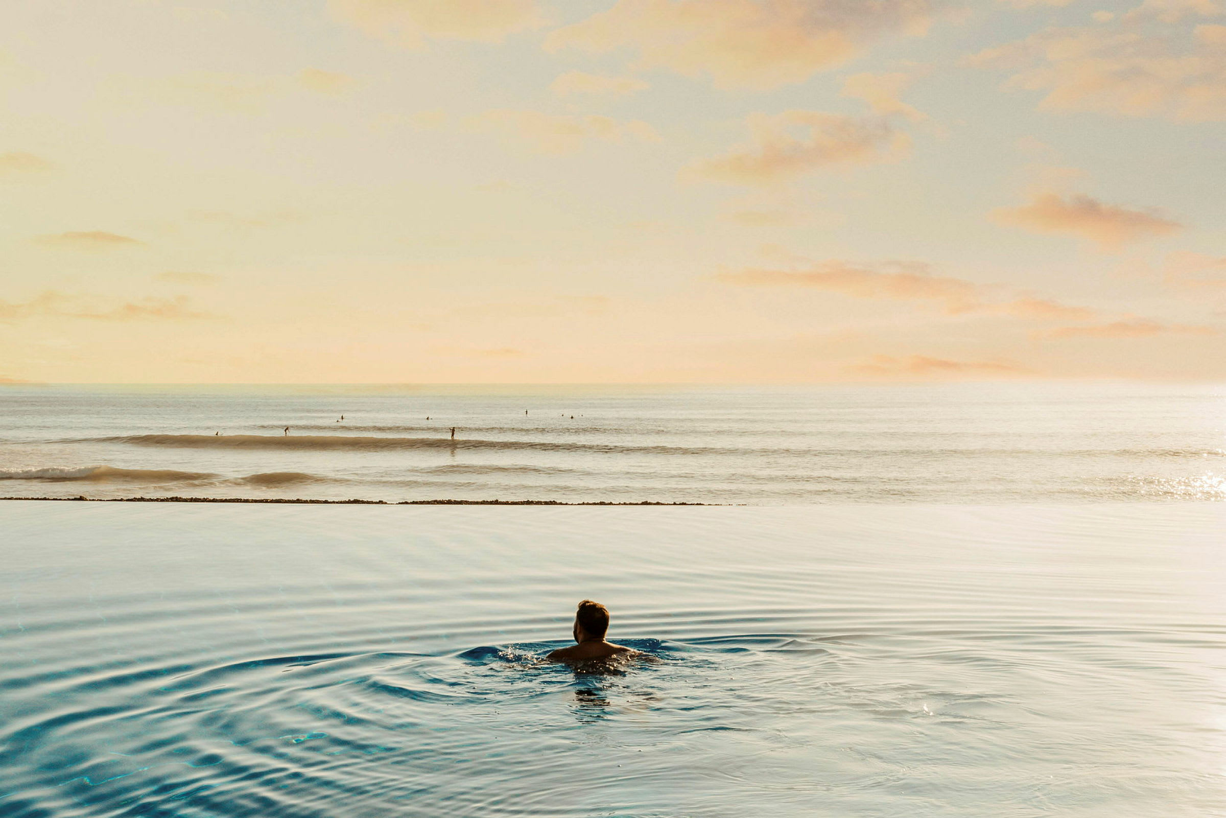 En person badar i en pool med utsikt över havet. (AI-genererad text)