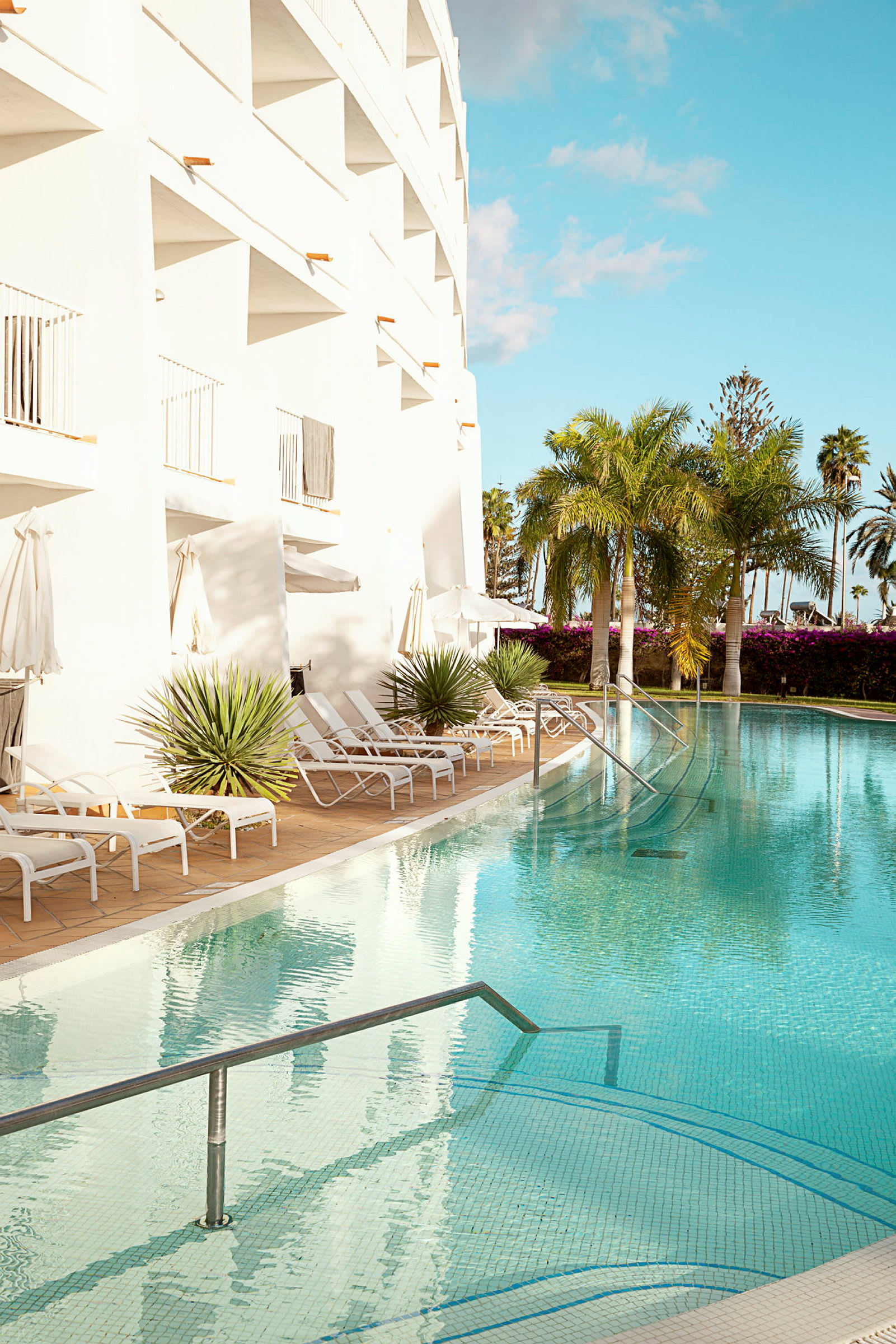 Utomhuspool vid hotell med solsängar och palmer. (AI-genererad text)