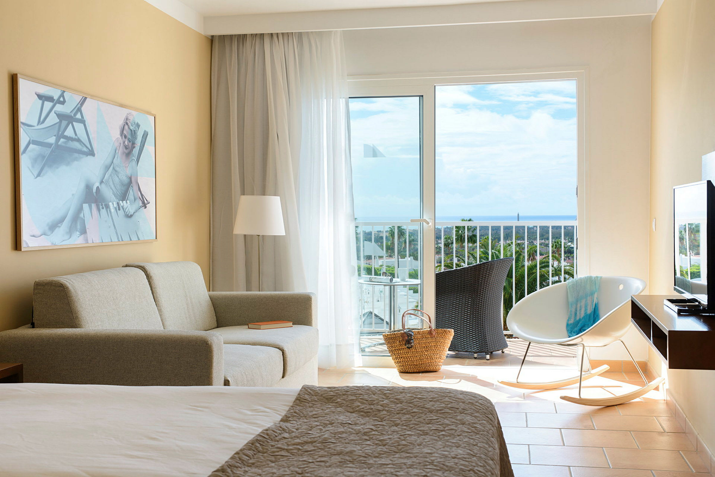 Ett hotellrum med soffa, stol och balkong med utsikt över havet. (AI-genererad text)