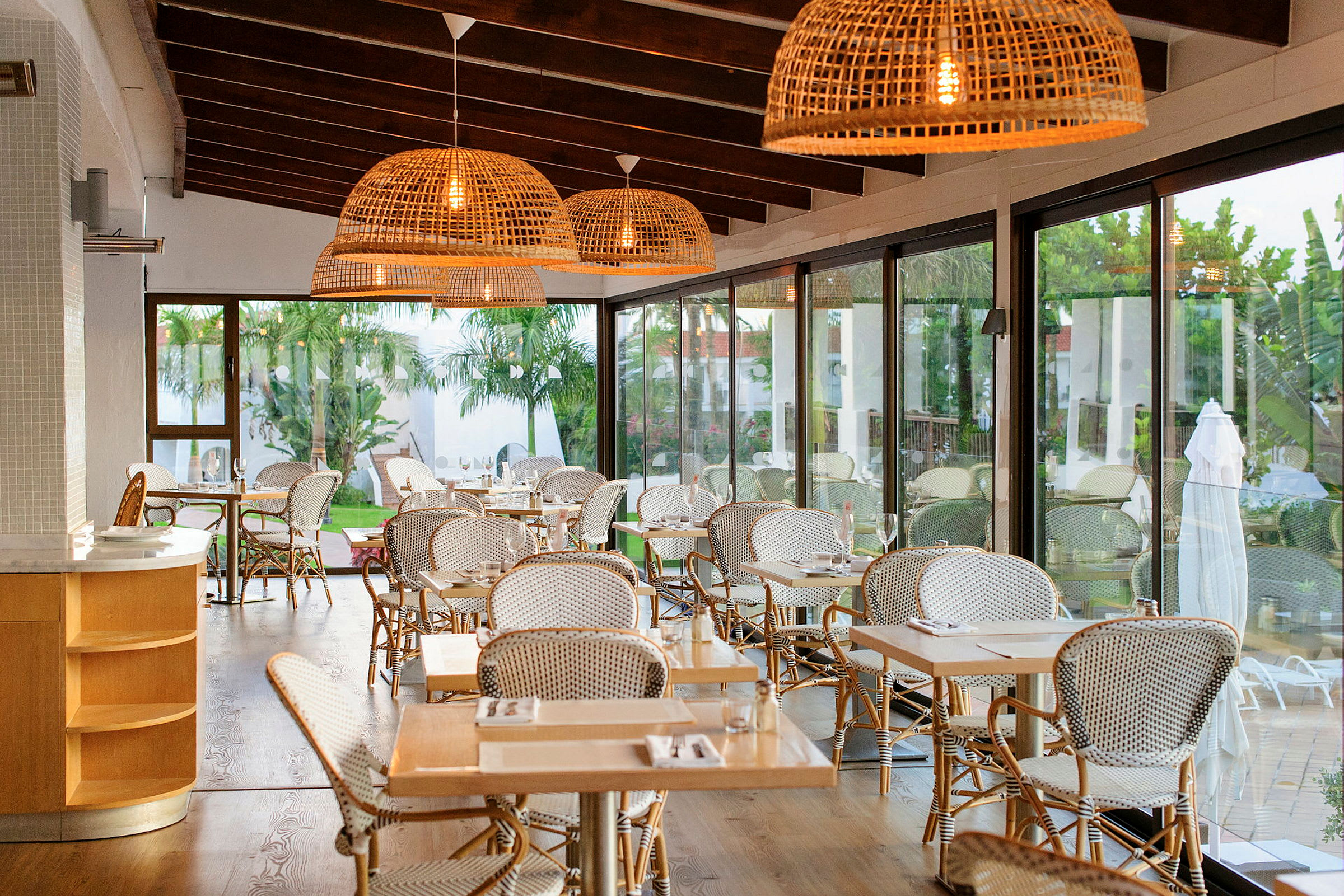 En interiör av en restaurang med stora glasfönster och träbjälkar i taket. (AI-genererad text)