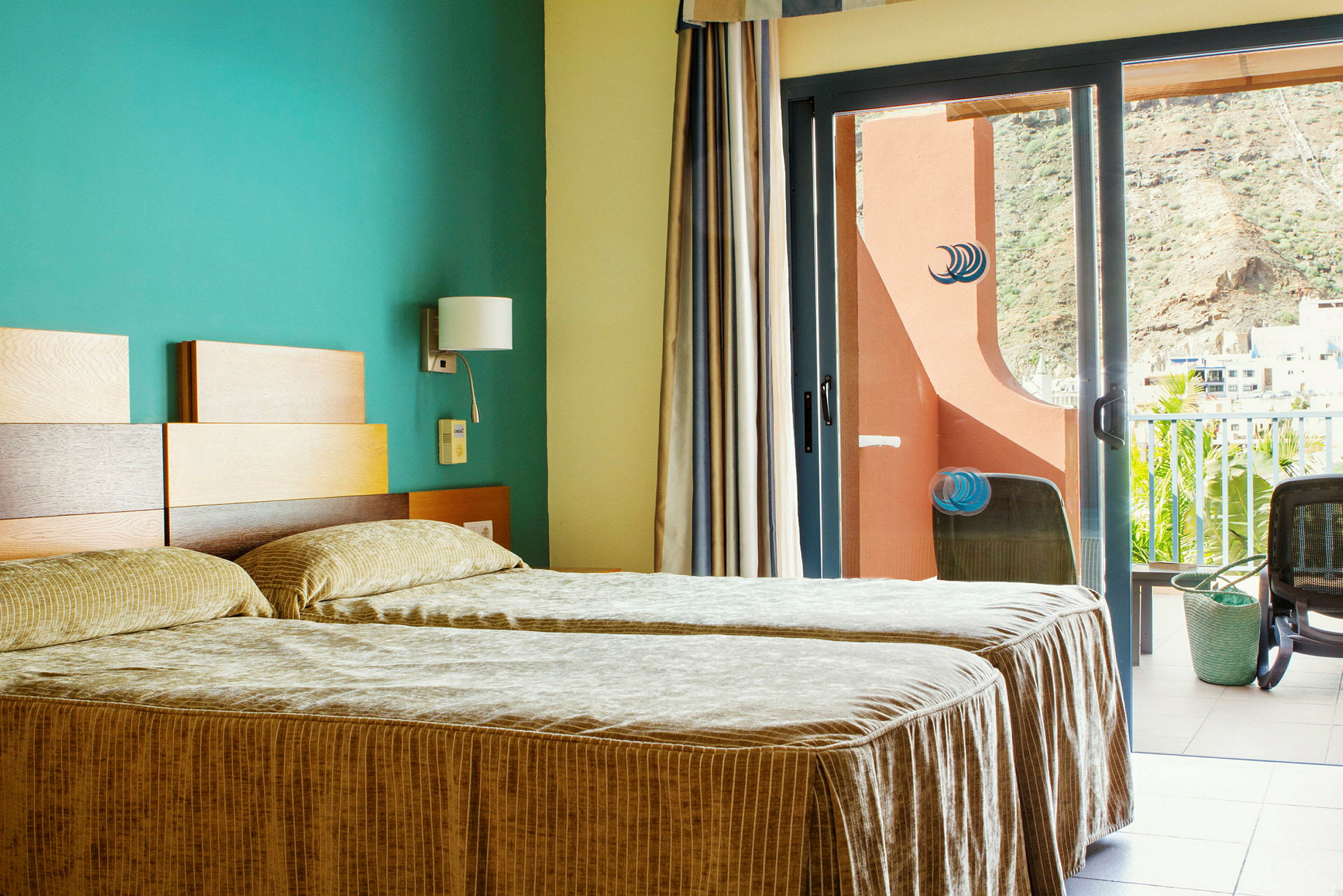 Hotellrum med två enkelsängar och en balkong med utsikt. (AI-genererad text)