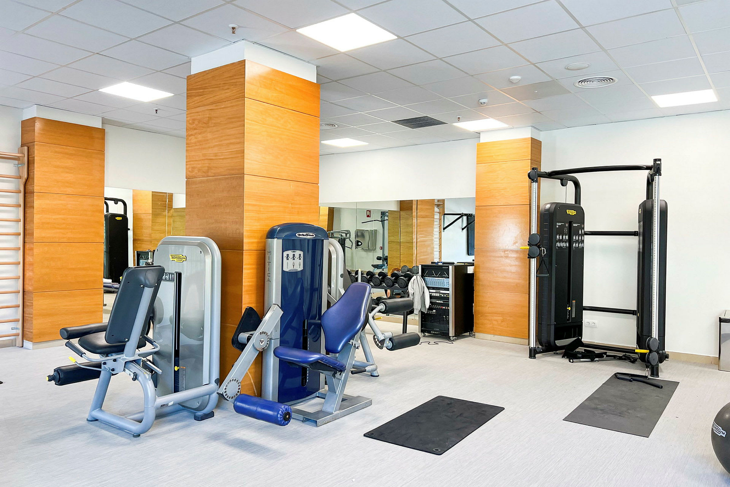 Bild av ett gym med träningsutrustning och speglar. (AI-genererad text)