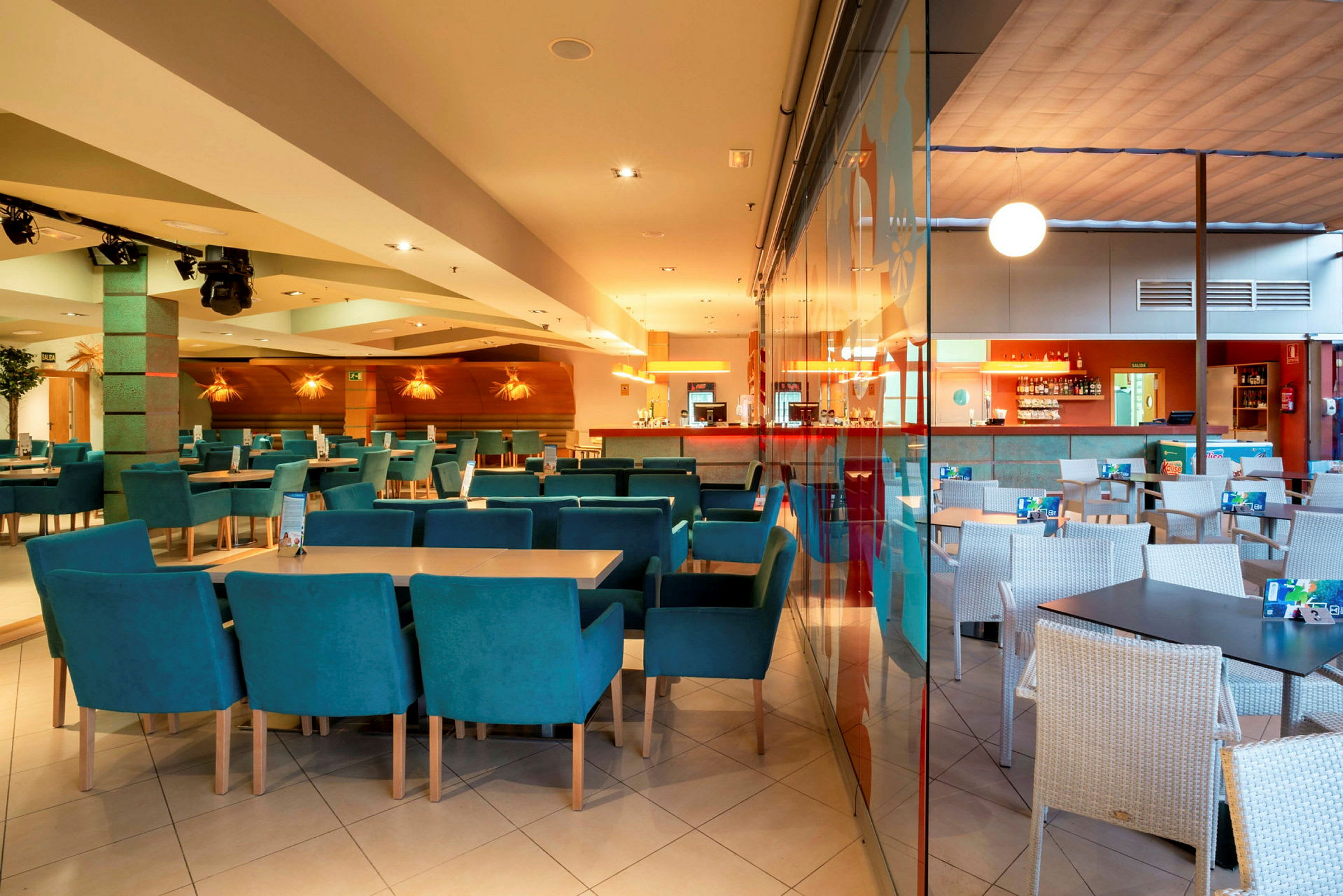 Interiör av en restaurang med bord och stolar, samt en bardisk i bakgrunden. (AI-genererad text)