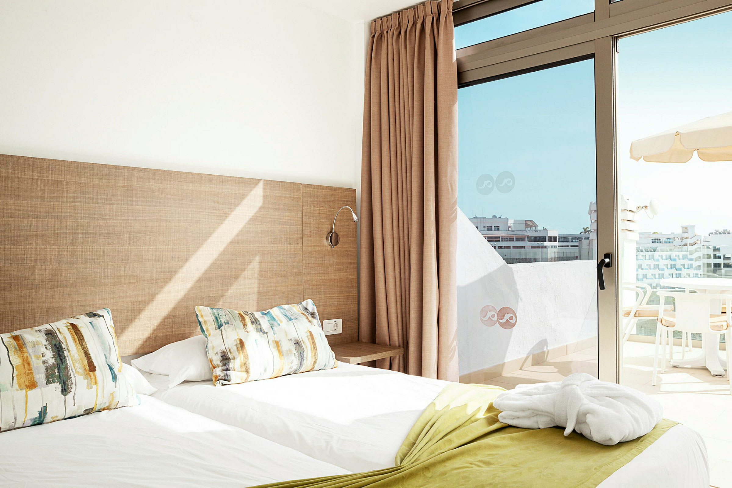 Hotellrum med två enkelsängar och en balkong med utsikt. (AI-genererad text)