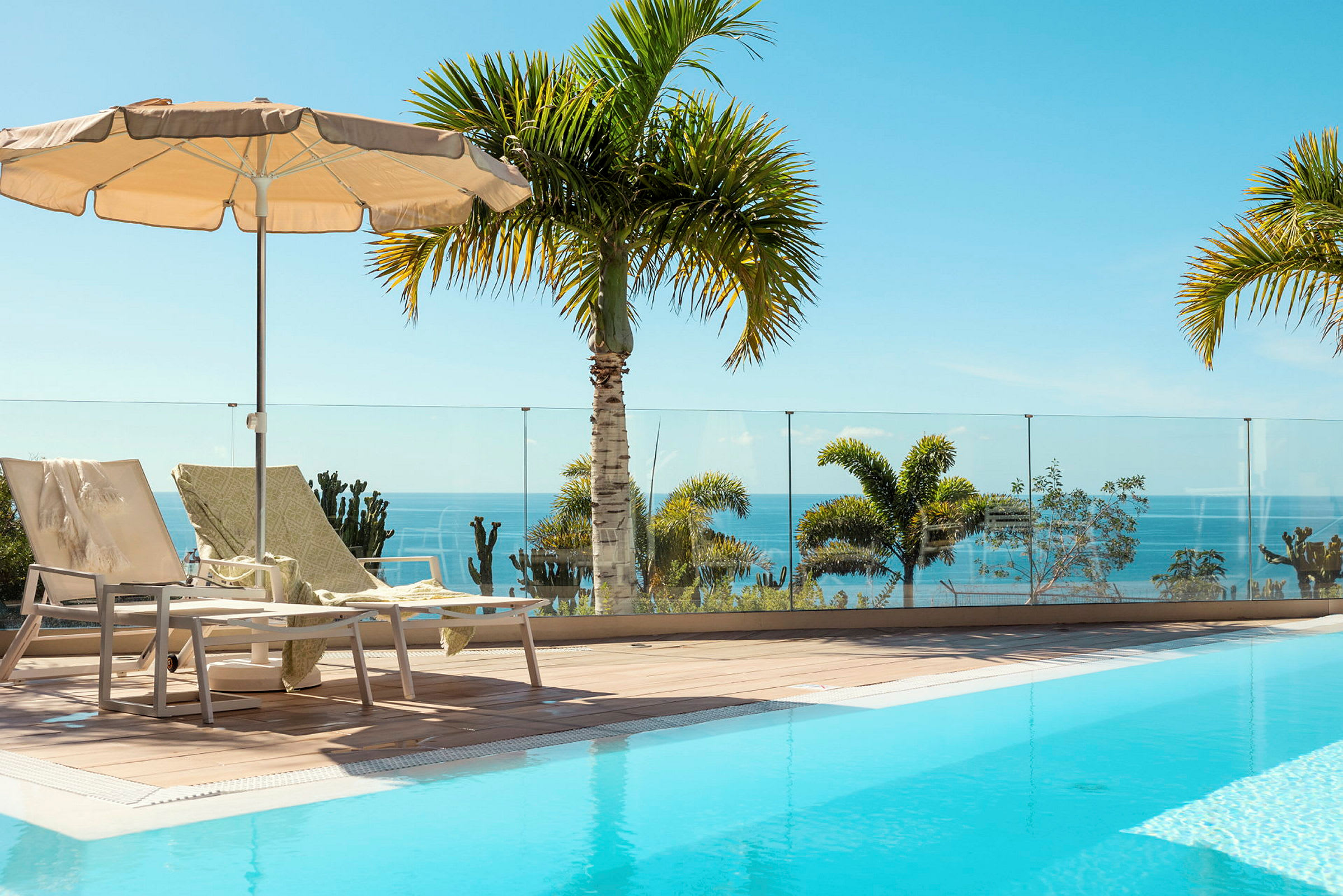 Solstolar och parasoll vid en pool med utsikt över havet. (AI-genererad text)