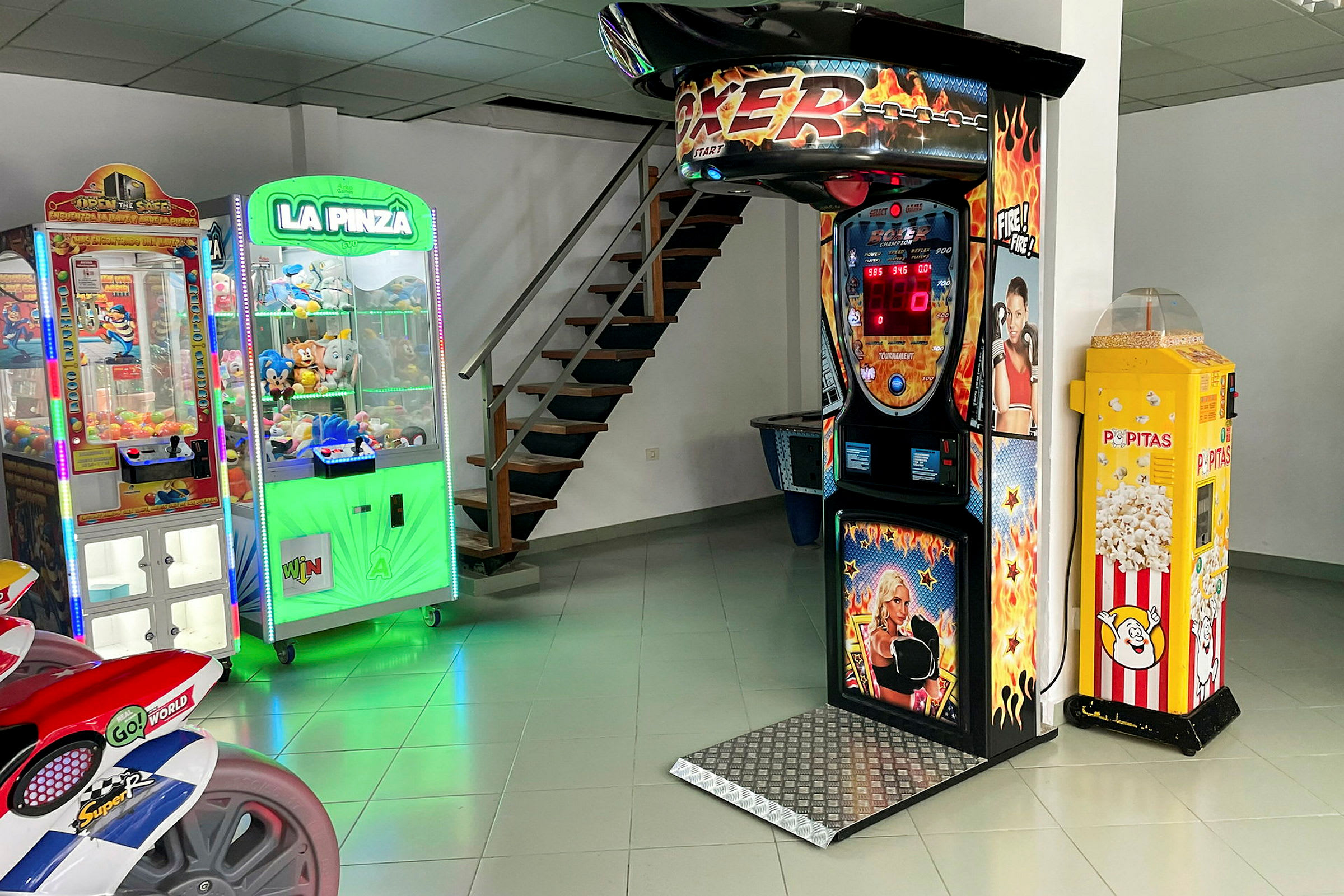 Ett rum med olika spelmaskiner, inklusive en boxningsmaskin, griparm-spel och en popcornautomat. (AI-genererad text)