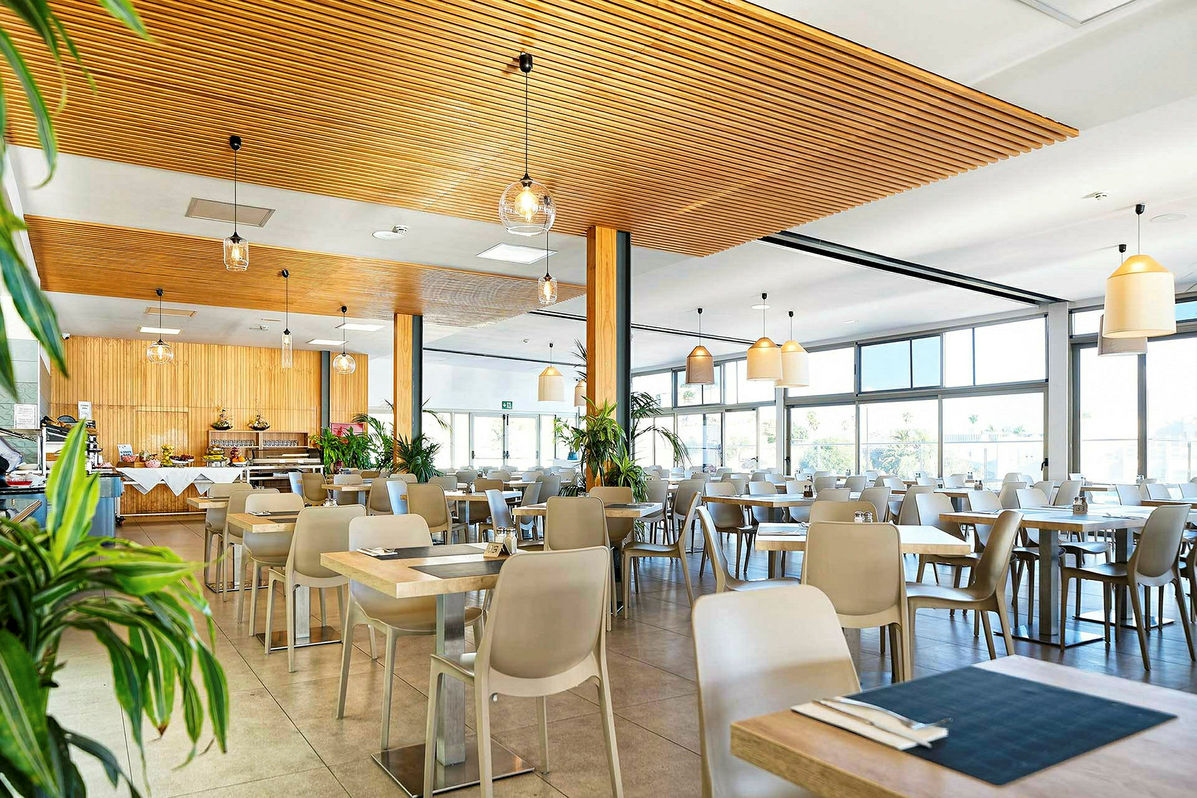 Bild på en ljus restaurang med trädetaljer och stora fönster. (AI-genererad text)