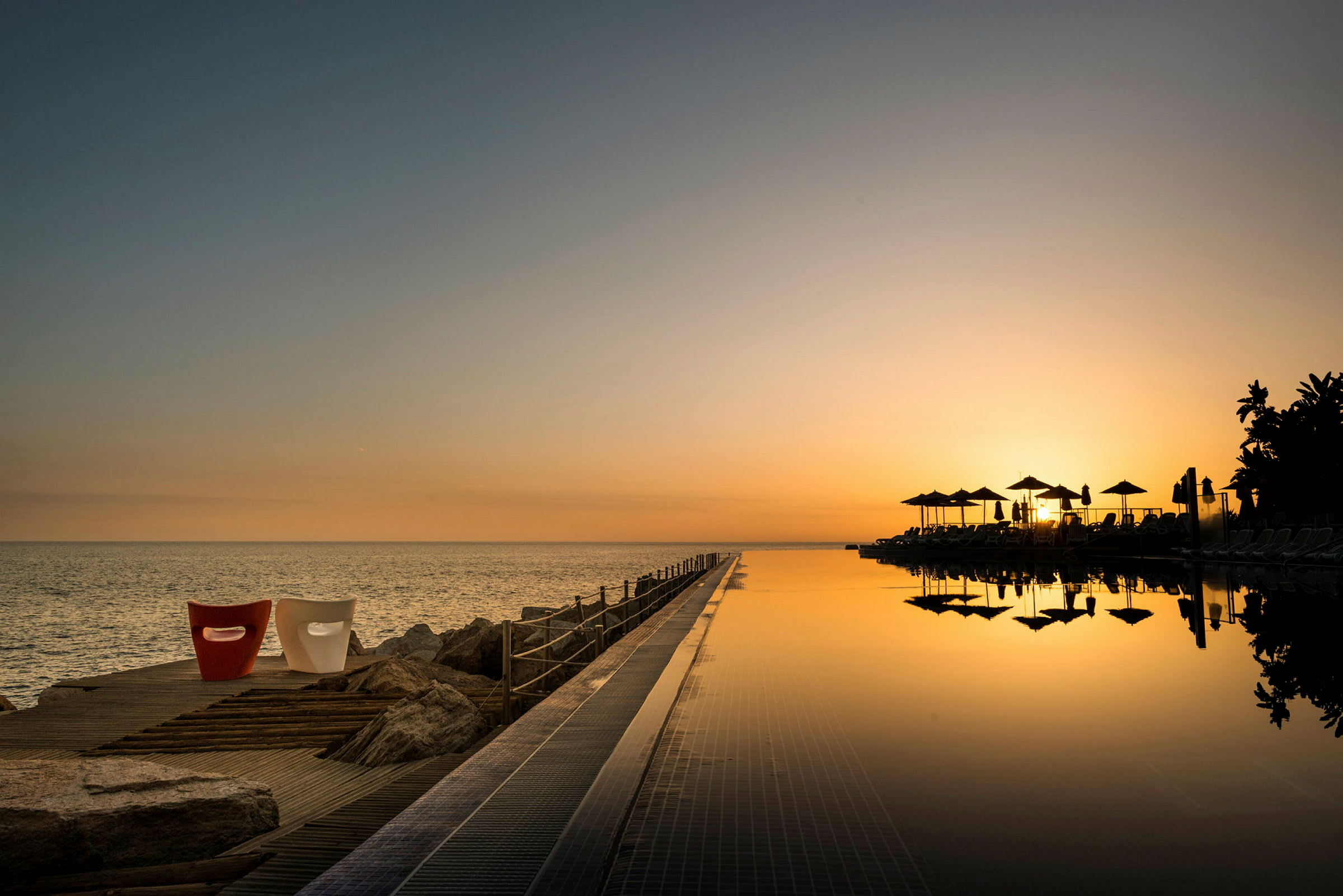 Soluppgång över havet med en infinitypool i förgrunden. (AI-genererad text)
