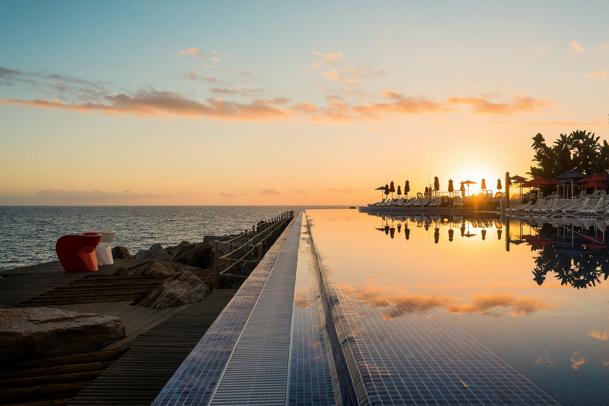 Solnedgång över havet och en infinitypool med solsängar. (AI-genererad text)