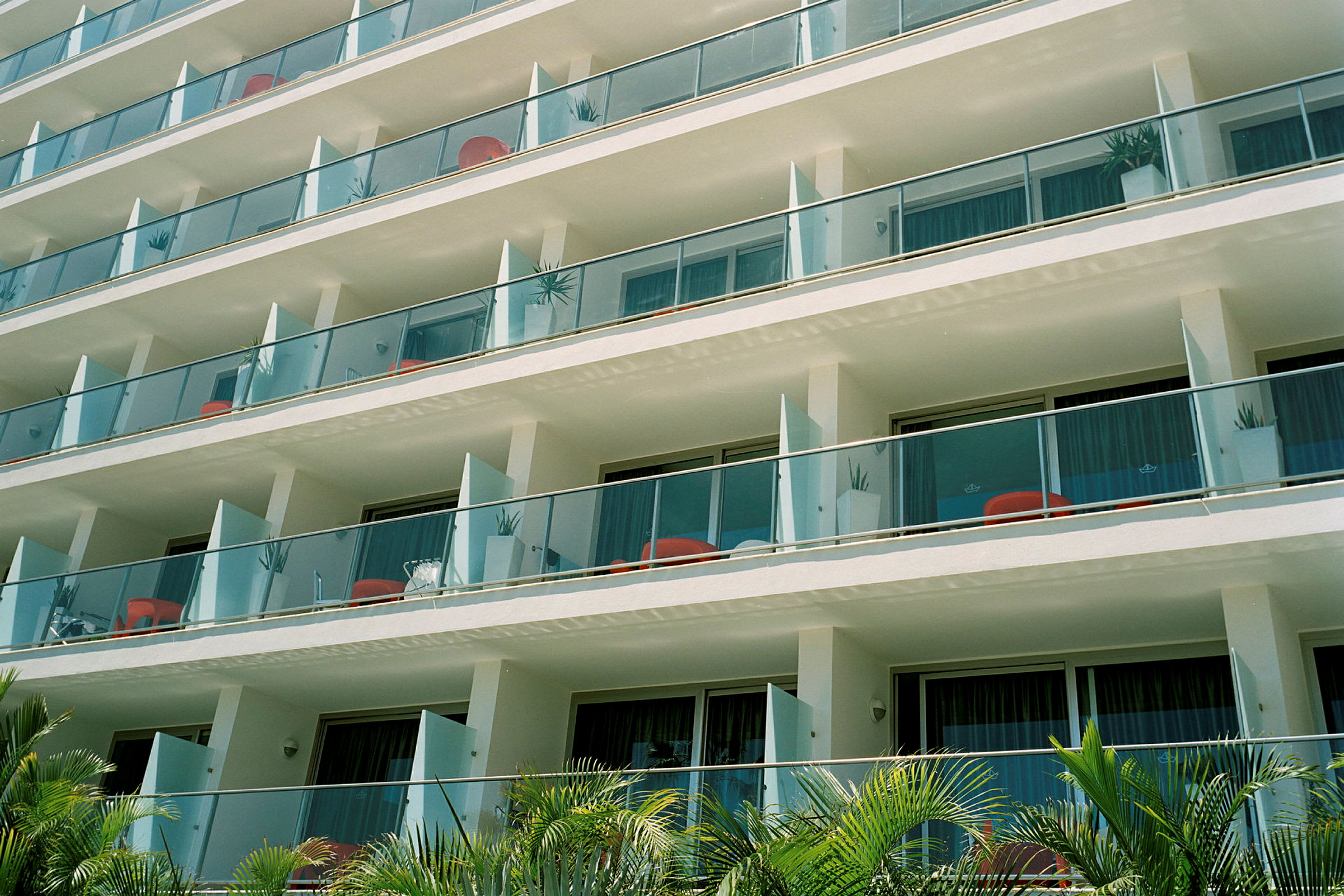 Flera hotellbalkonger med glasräcken på en byggnad. (AI-genererad text)