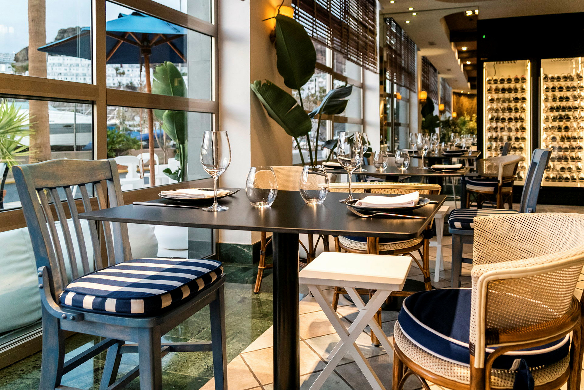 Elegant restaurang med dukade bord och stolar nära stora fönster. (AI-genererad text)
