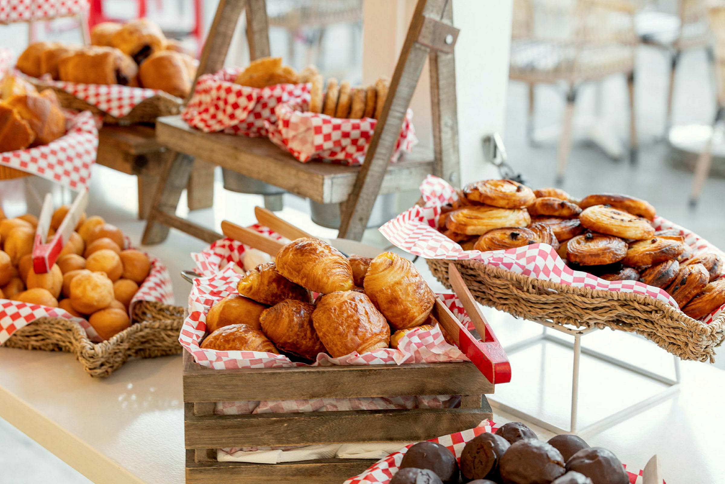 En display med olika sorters bakverk, inklusive croissanter, bullar och danska wienerbröd, i korgar och trälådor. (AI-genererad text)