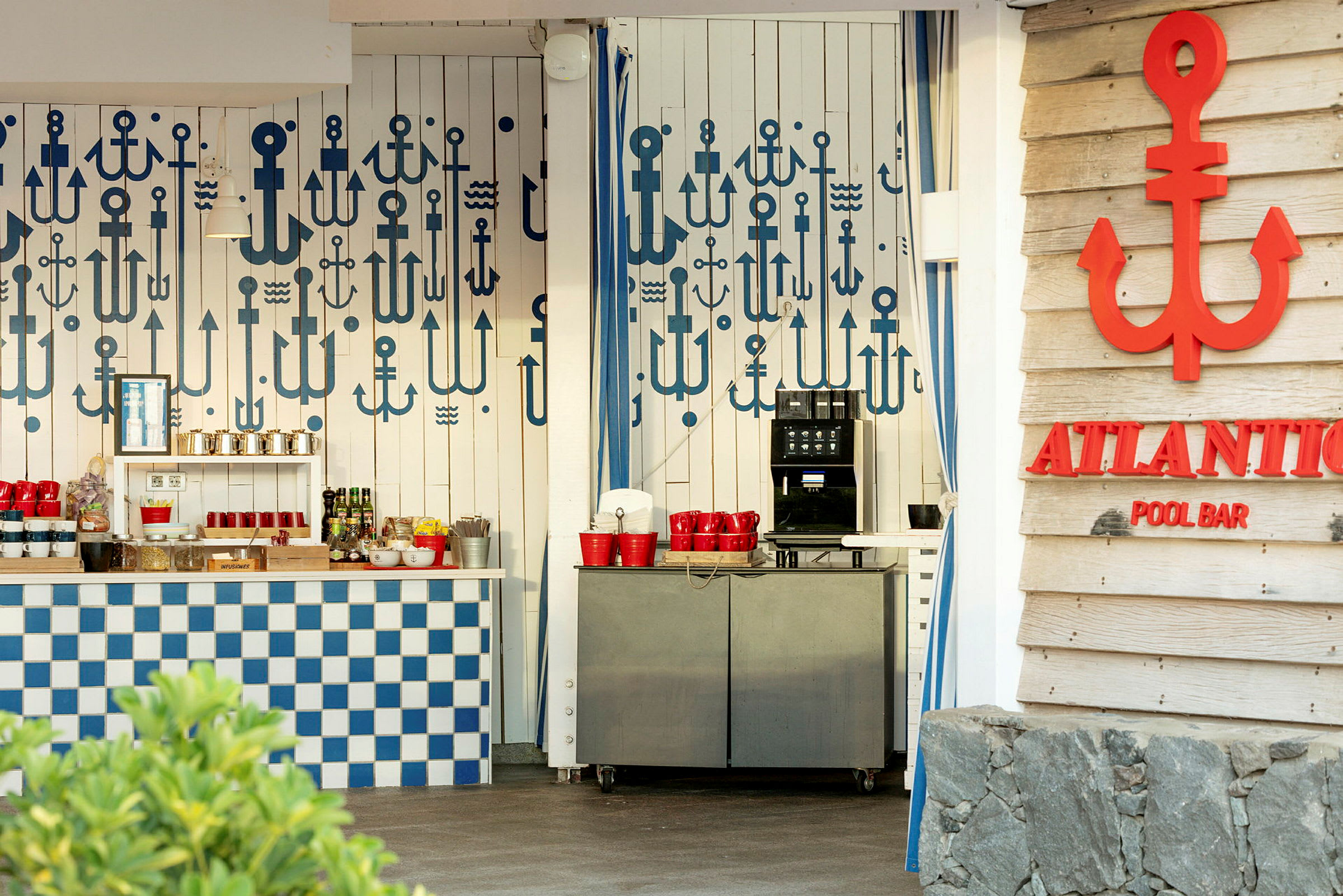 En poolbar med en vägg dekorerad med olika blåa ankmotiv, en serveringsdisk med blått och vitt rutmönster och en automat med röda muggar. (AI-genererad text)