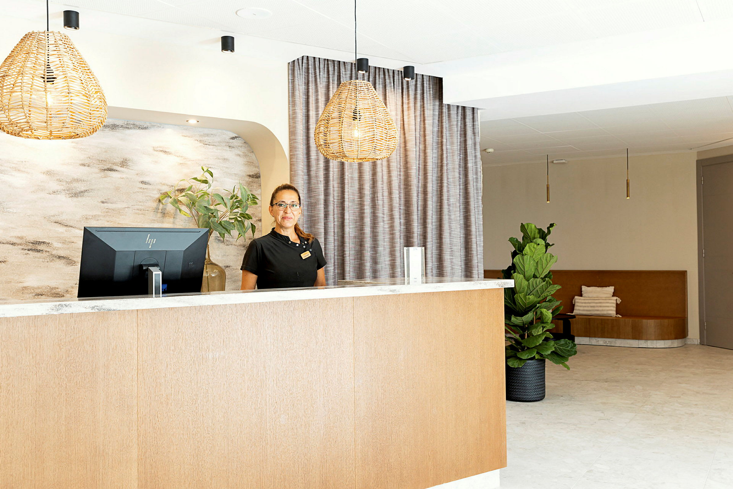 Reception med disk och dator, väggdekorationer och inredningsdetaljer som gardiner och grön växt. (AI-genererad text)