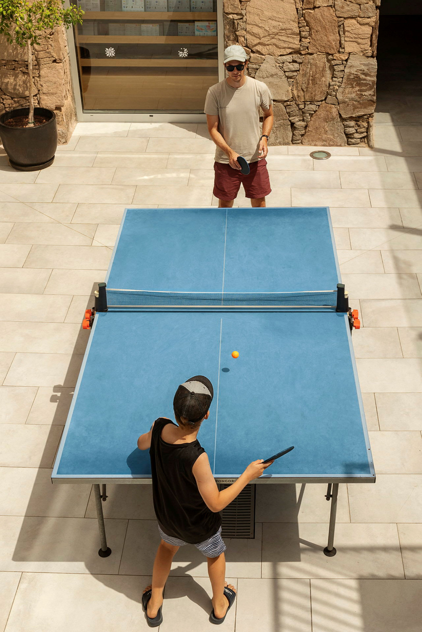 Två personer spelar bordtennis utomhus. (AI-genererad text)