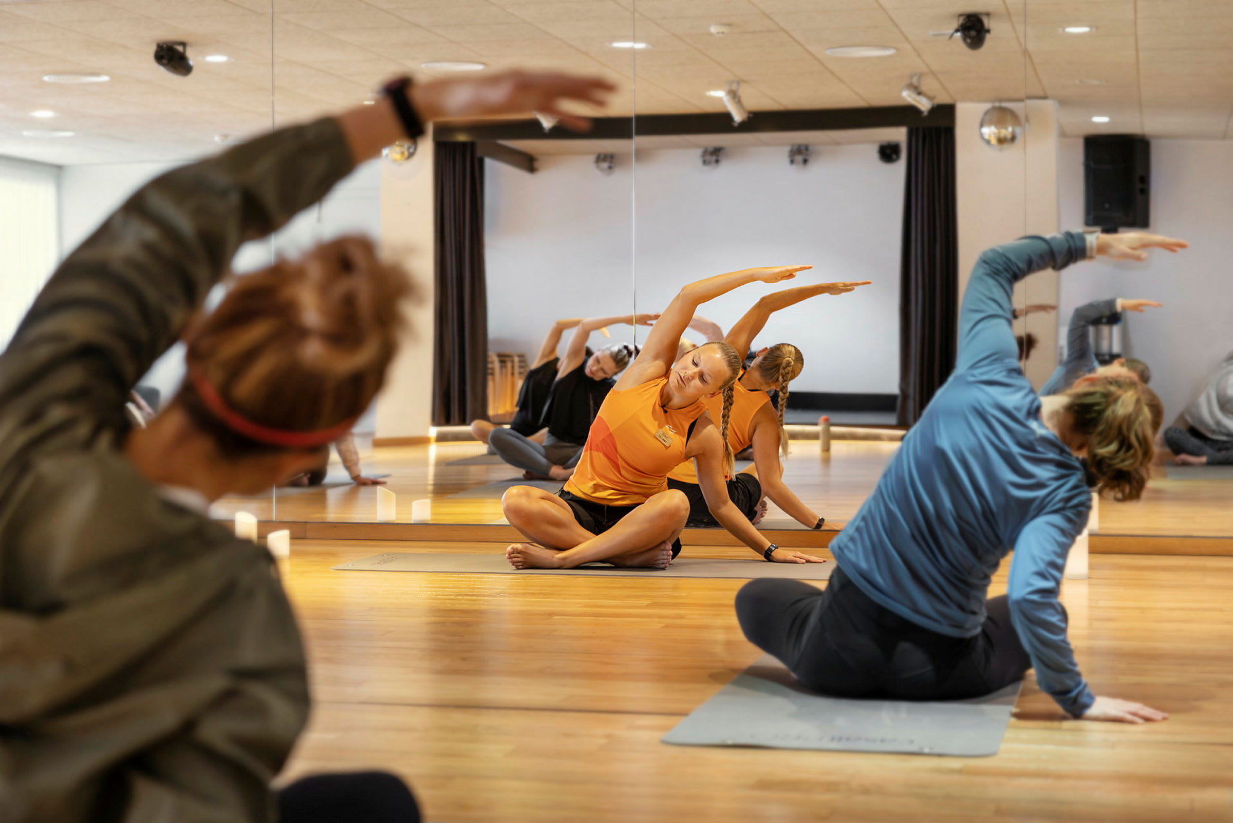 En grupp människor tränar i yogapositioner i en spegelsal. (AI-genererad text)