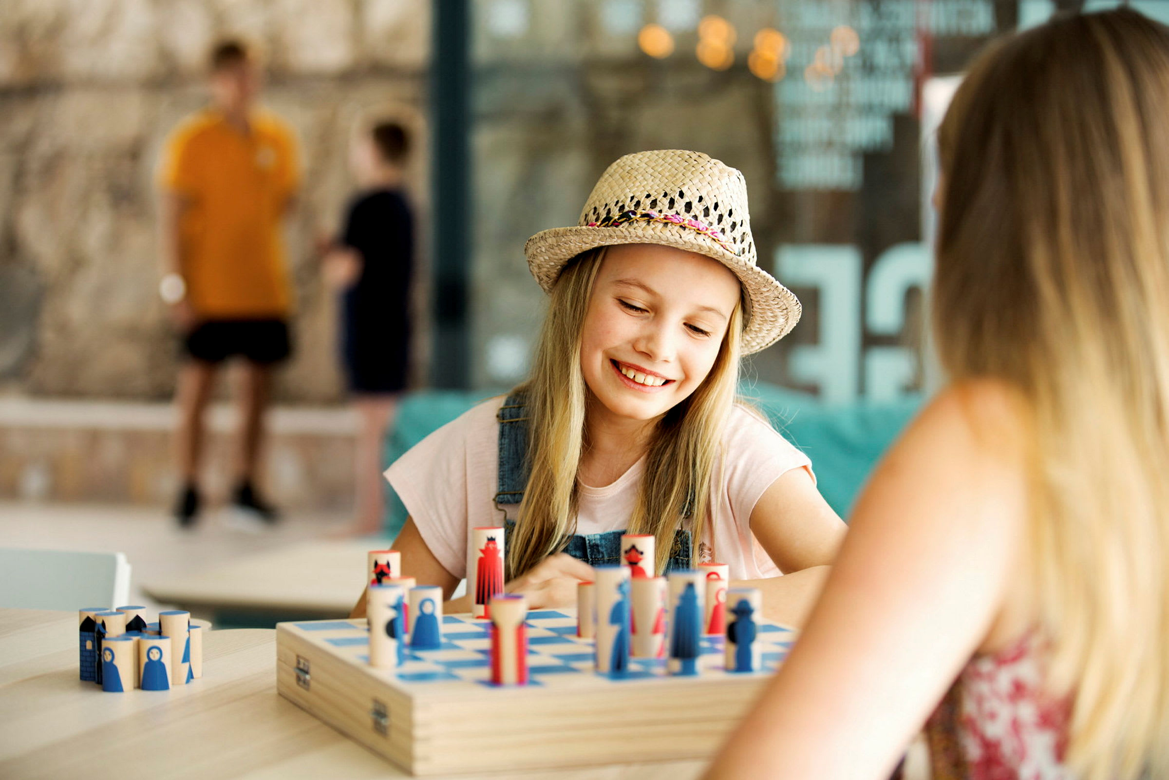 Två personer spelar ett strategiskt brädspel vid ett bord. (AI-genererad text)